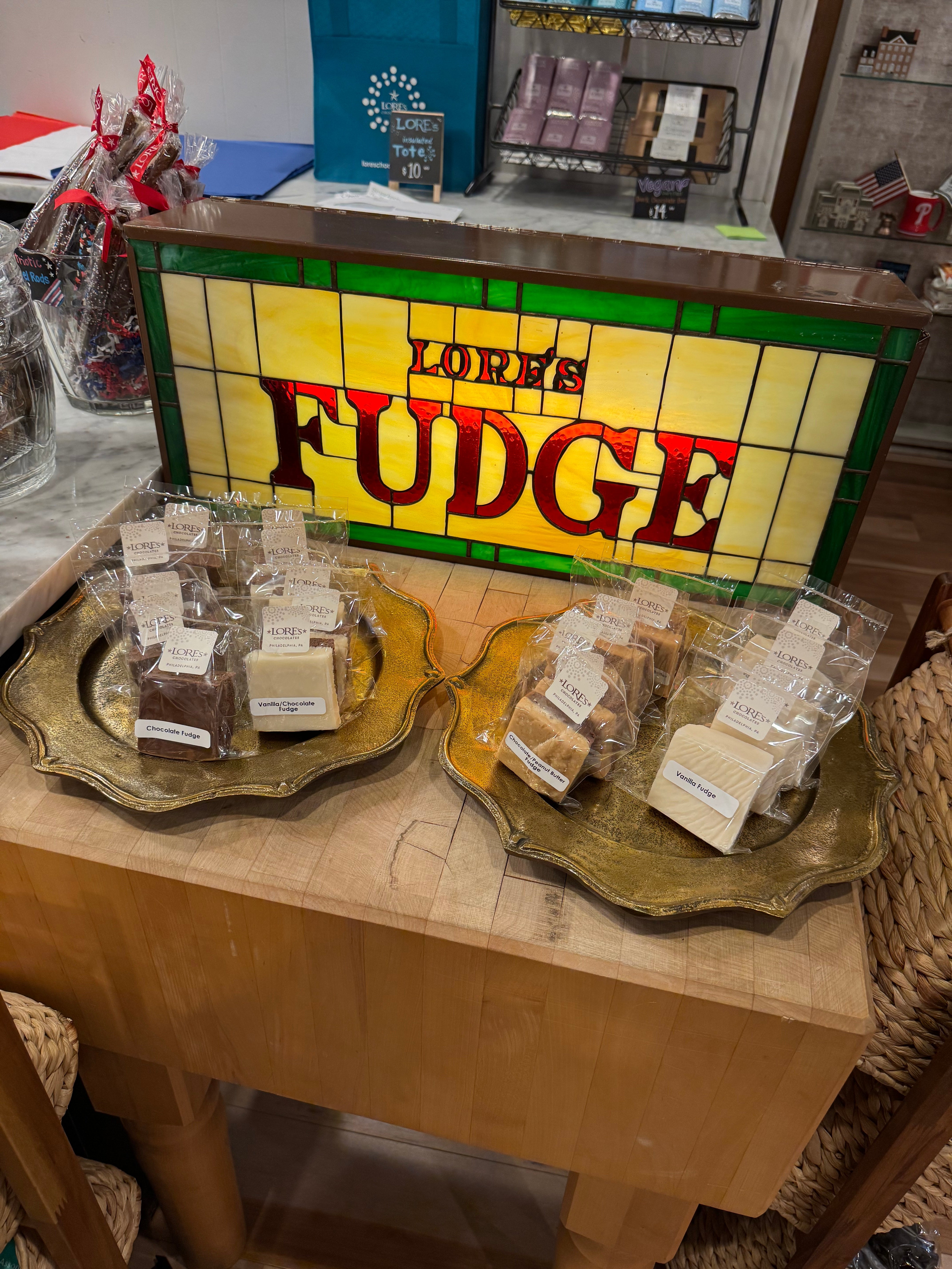 Sign with Lore's Fudge behind the selection of Fudge Flavors in the philadelphia store