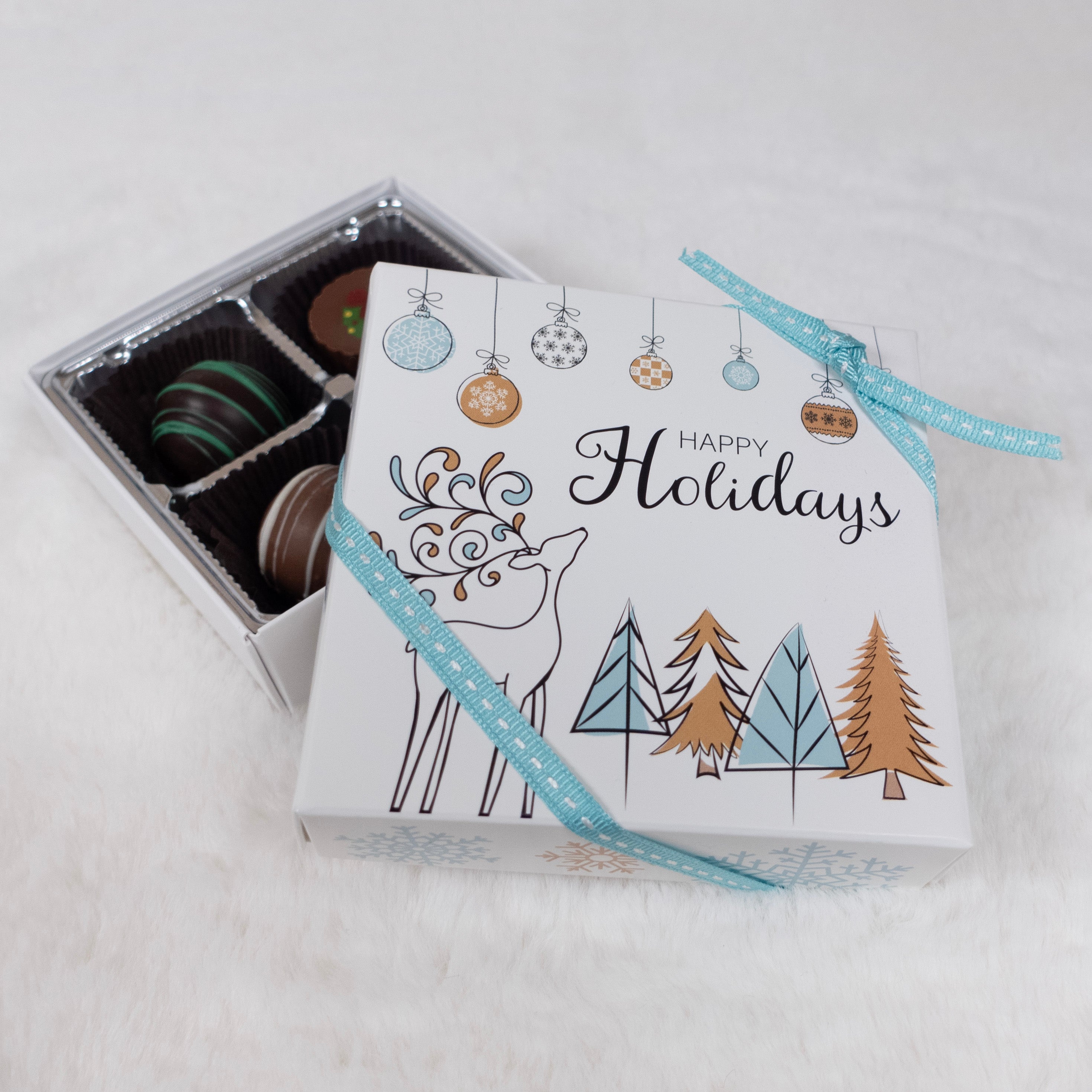 Box of chocolates with a 'Happy Holidays' design featuring trees and a reindeer on a white background.