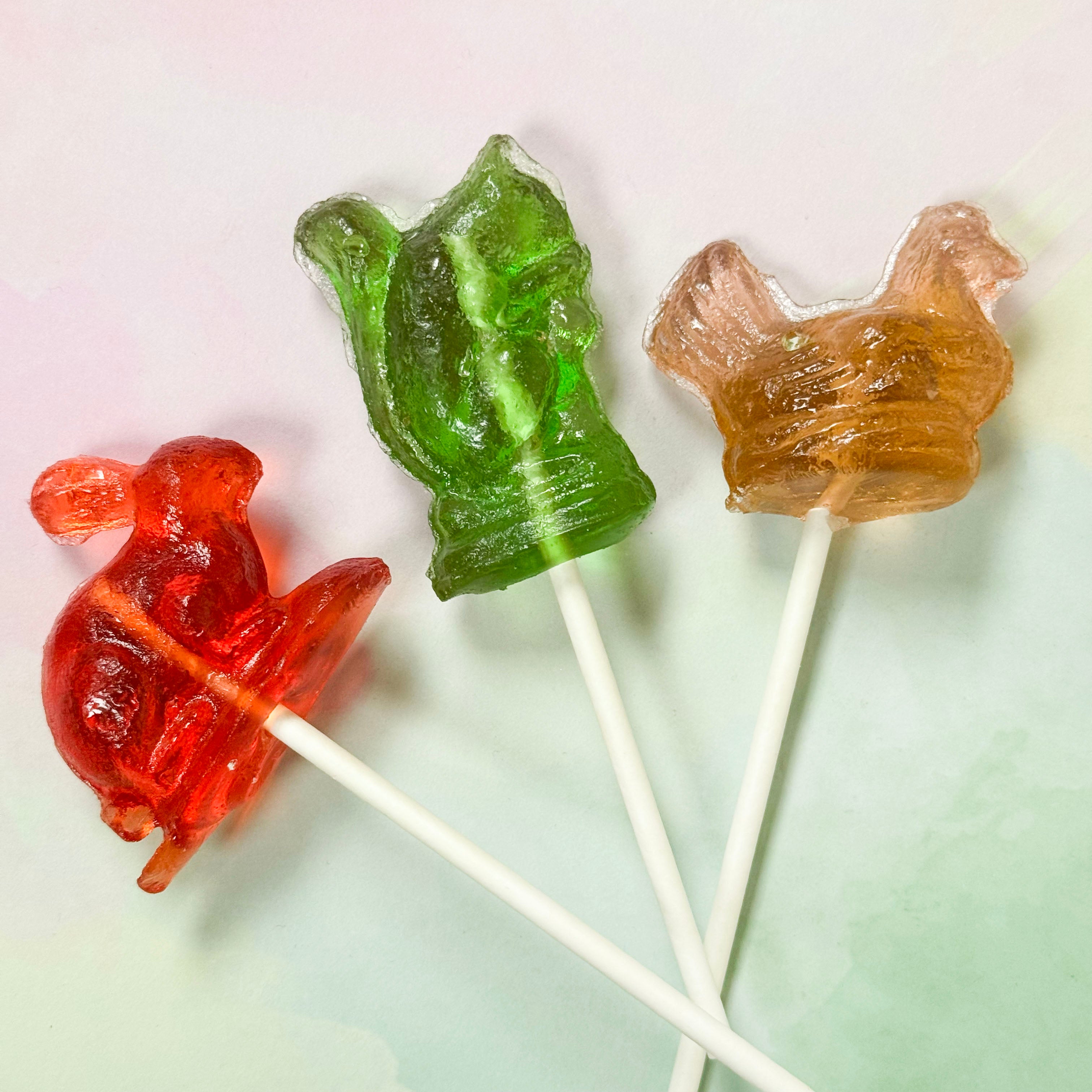 Three animal-shaped lollipops on sticks against a light background