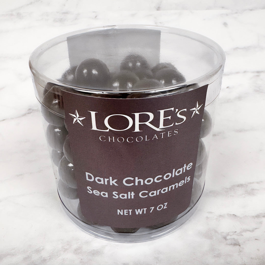 clear container of Lore's Chocolates Dark Chocolate Sea Salt Caramels on a marble surface