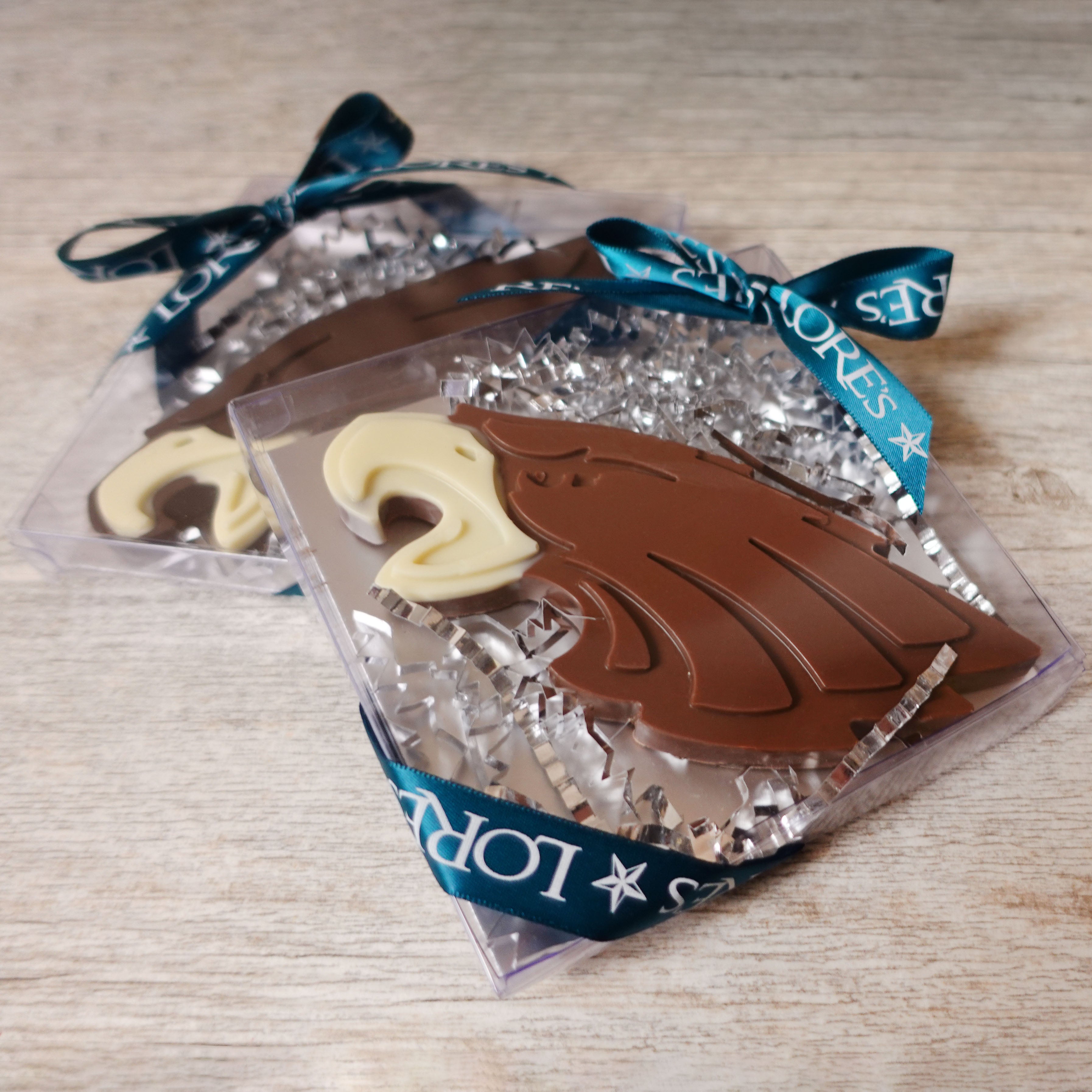 Chocolate shaped as Eagles Logo in clear packaging with green ribbon on a wooden surface