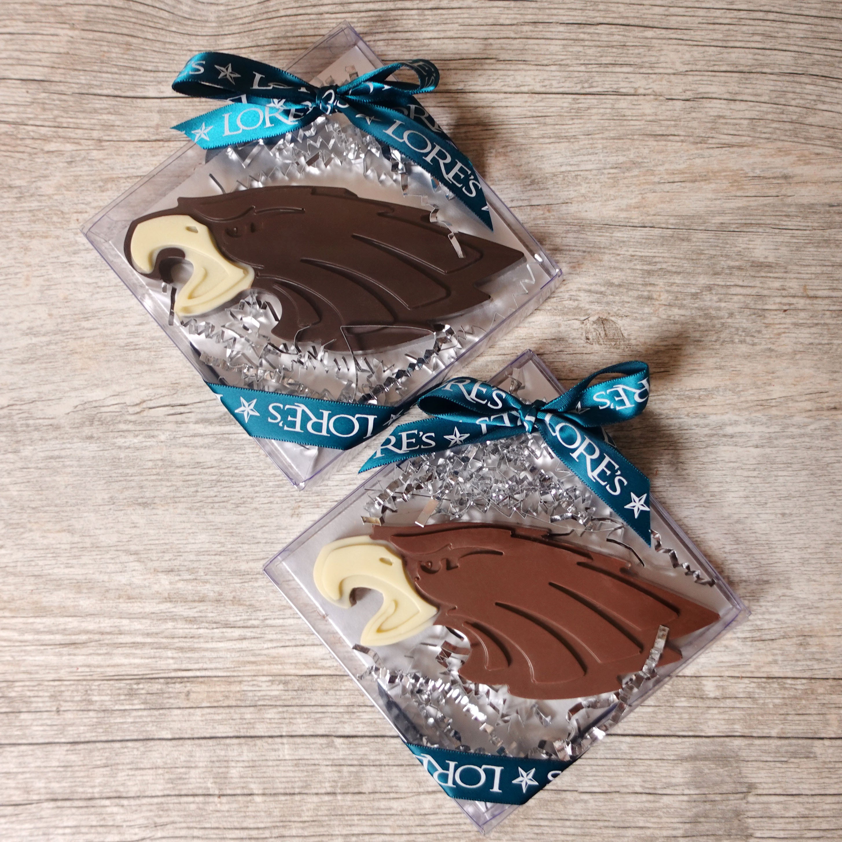 Chocolate eagles in clear packaging with ribbons on a wooden surface