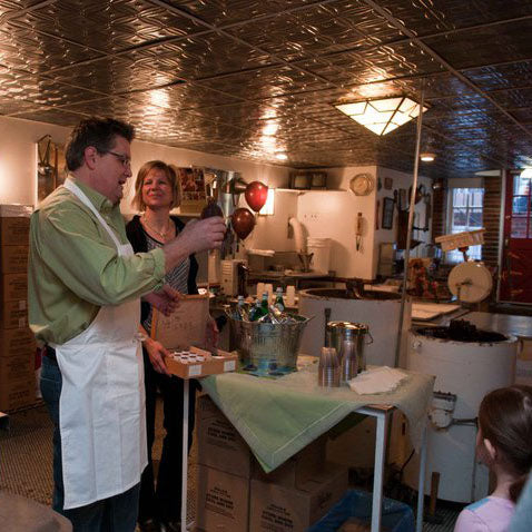 Maureen and Tony showing how chocolate is made to children in the previous chocolate factory beneath the philadelphia retail store.