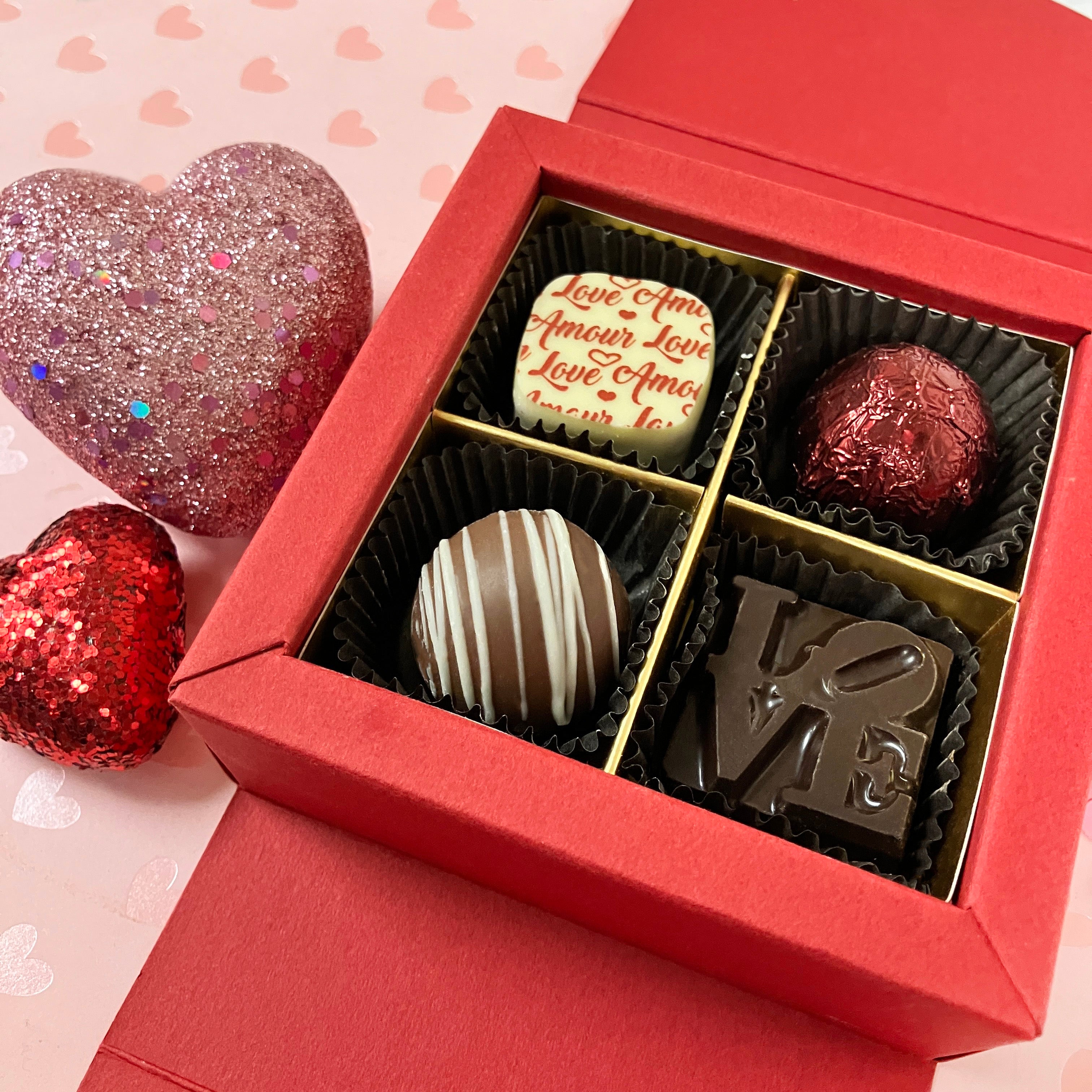 Red gift box with truffles and chocolates and a heart-shaped object on a pink background