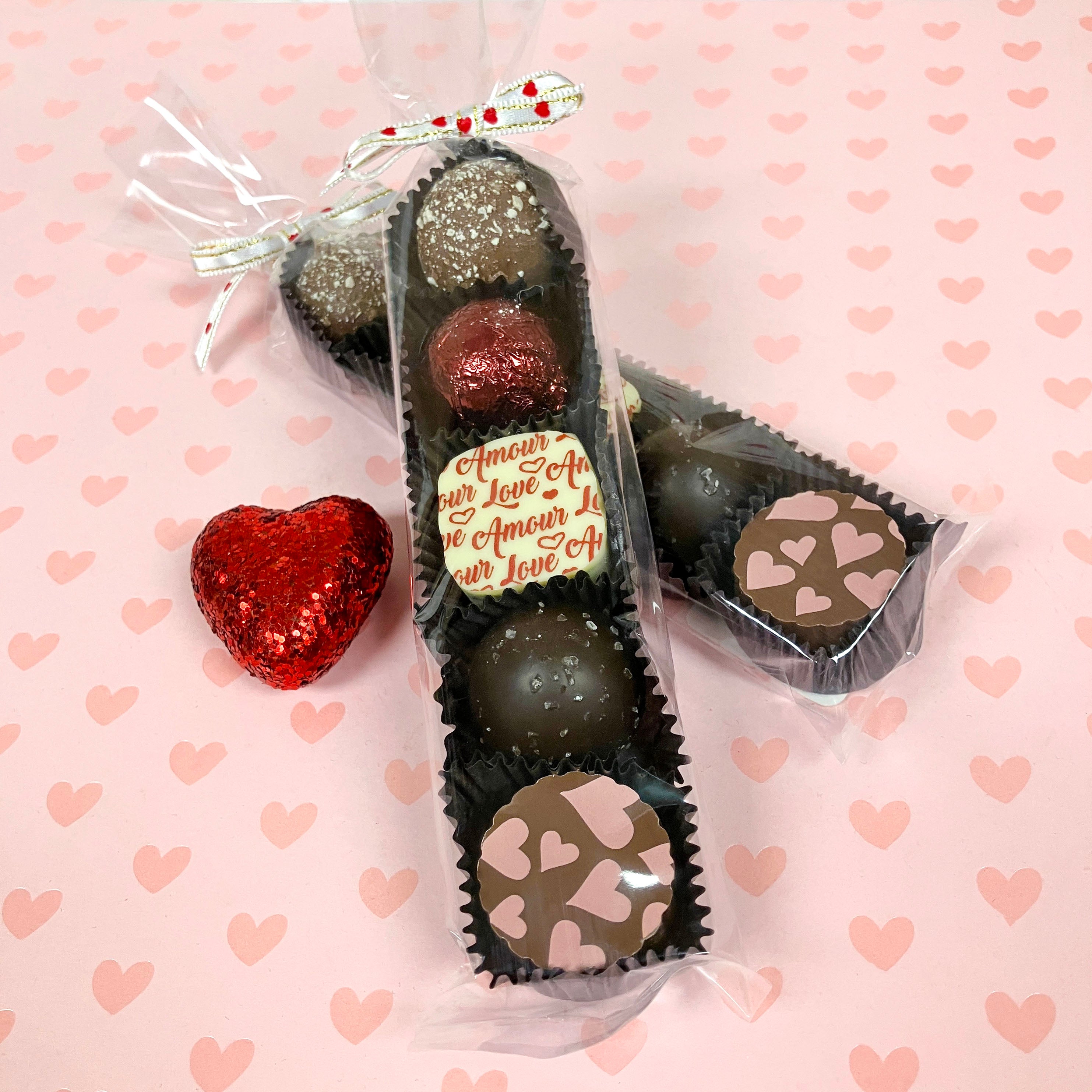 cellophane sleeve of chocolate truffles on a pink background with heart patterns