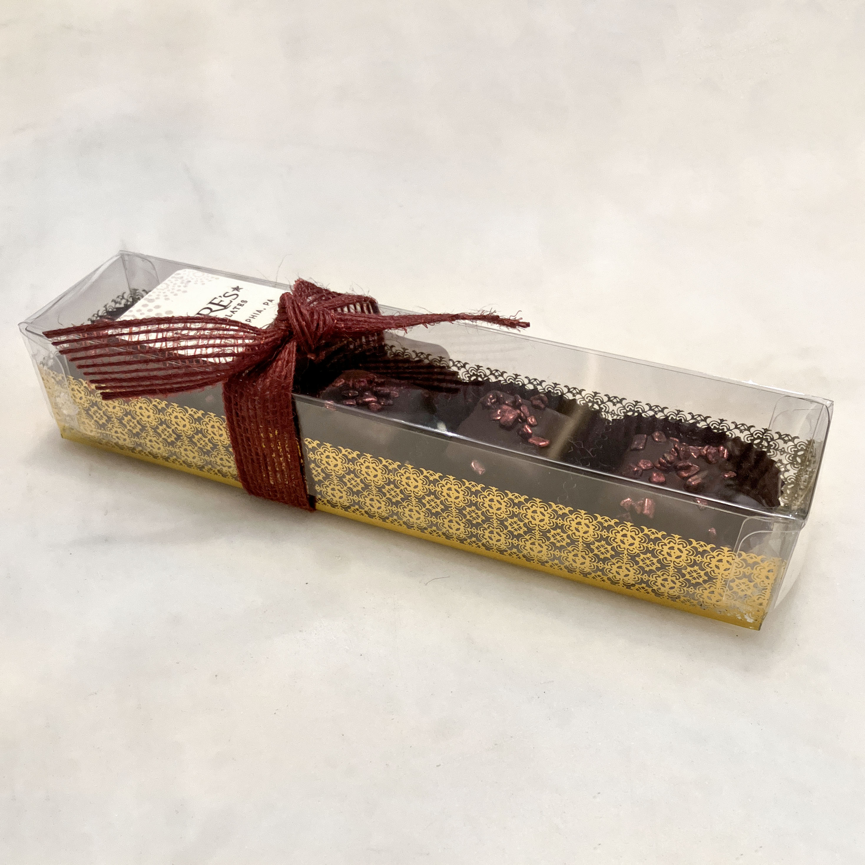 dark Chocolate caramels in a clear box with a decorative bow on a light background