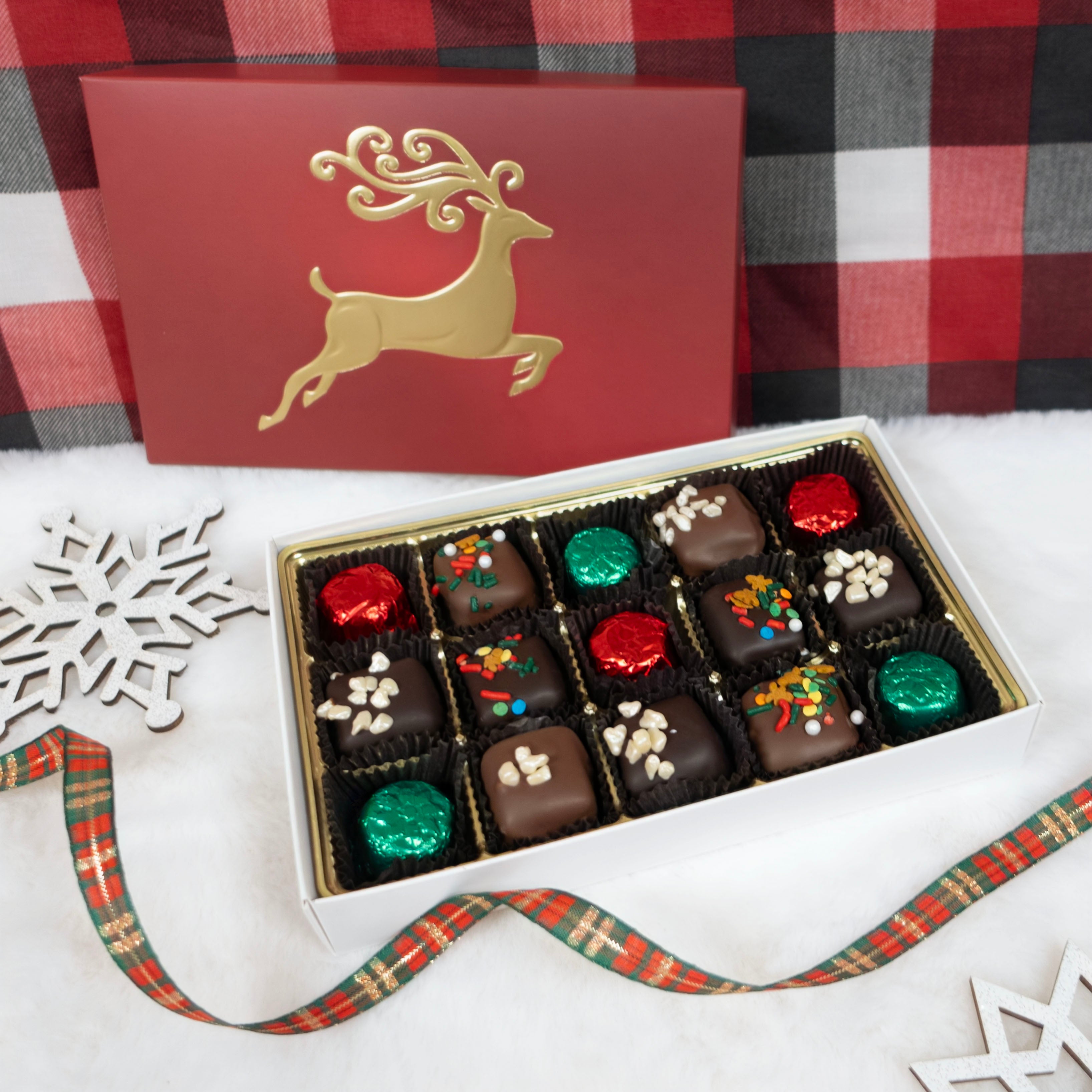 Box of chocolates with a gold reindeer design on a red and black checkered background