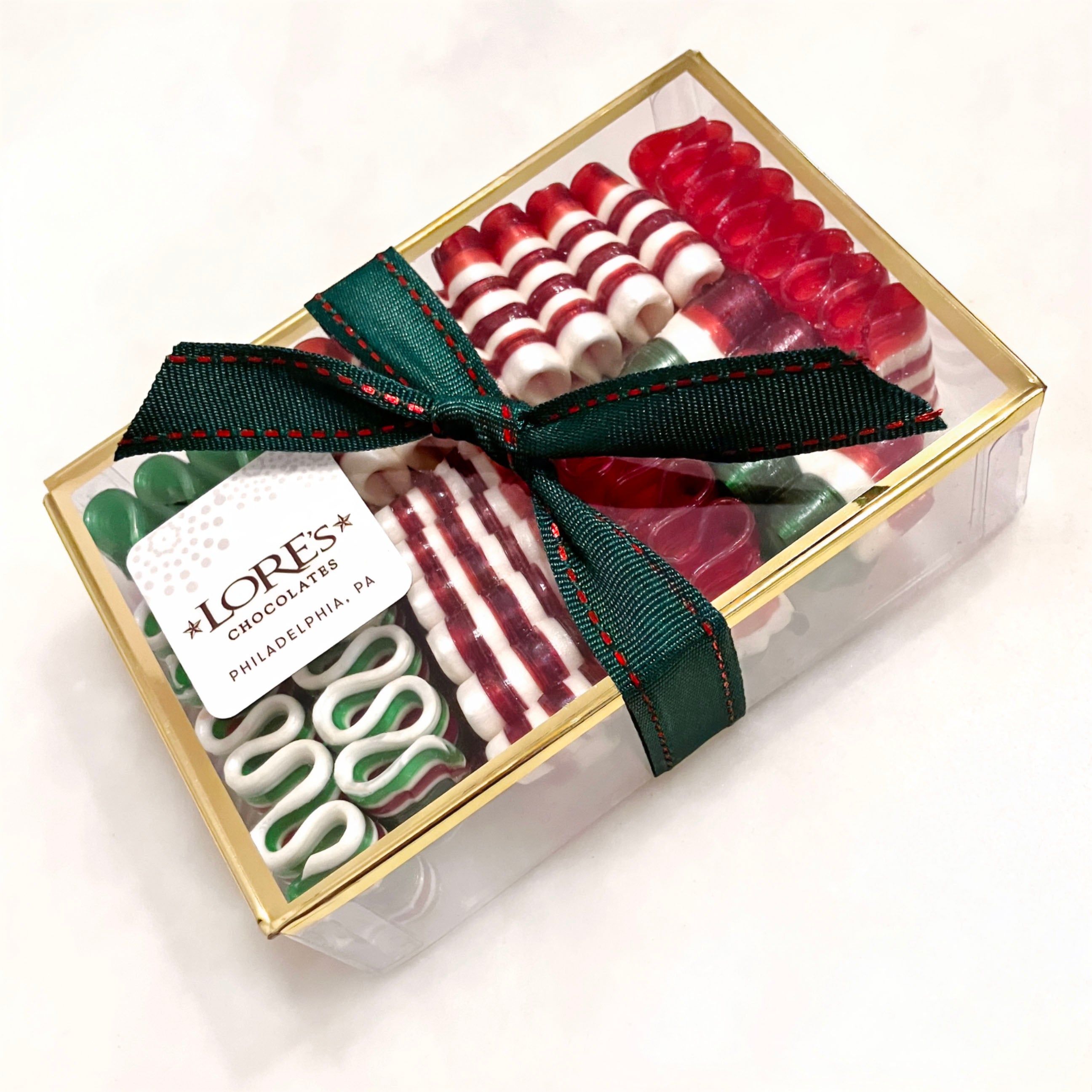 Box of assorted hard candy ribbons with a green ribbon and LORE'S Chocolates label on a white background