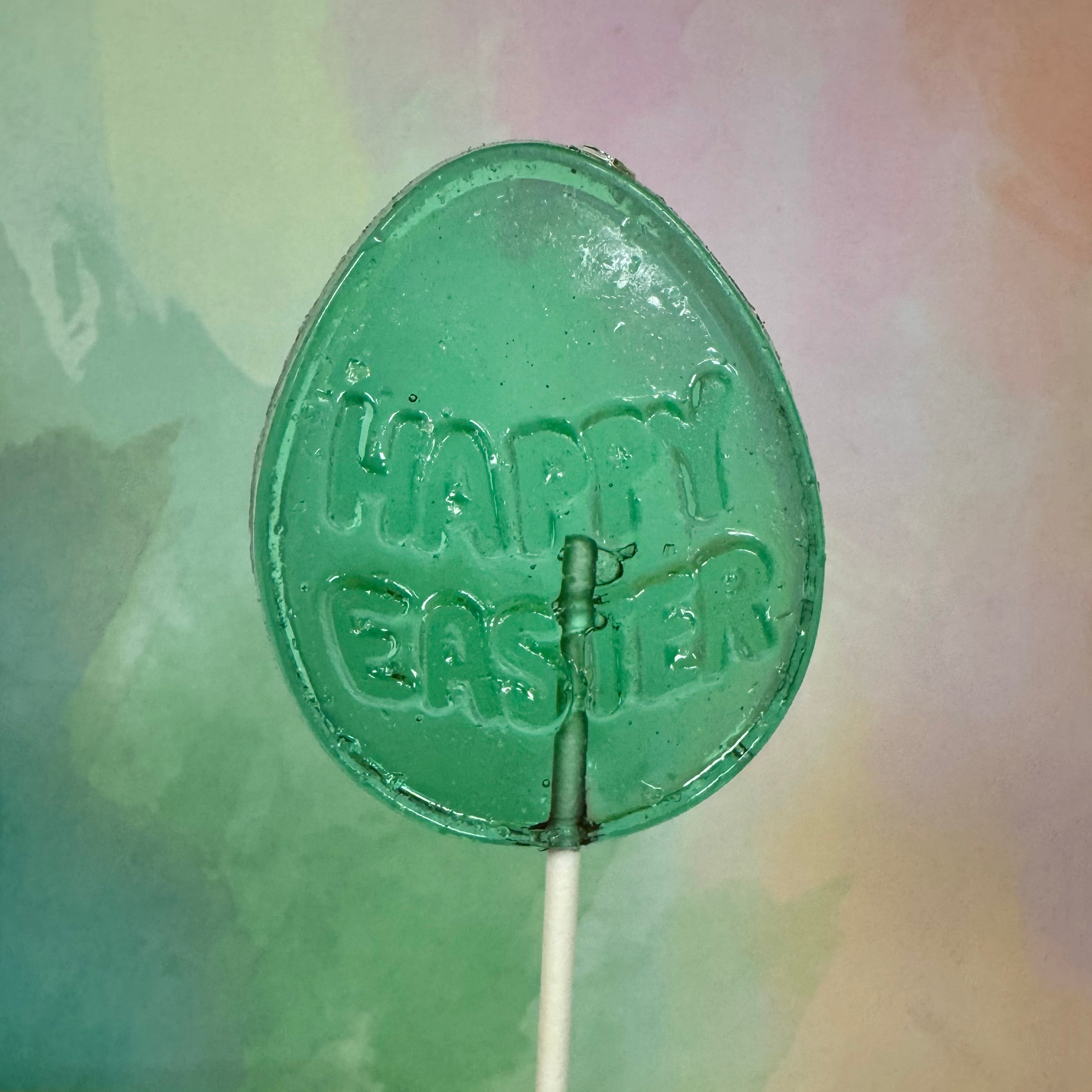 Green egg-shaped lollipop with 'Happy Easter' text on a colorful background