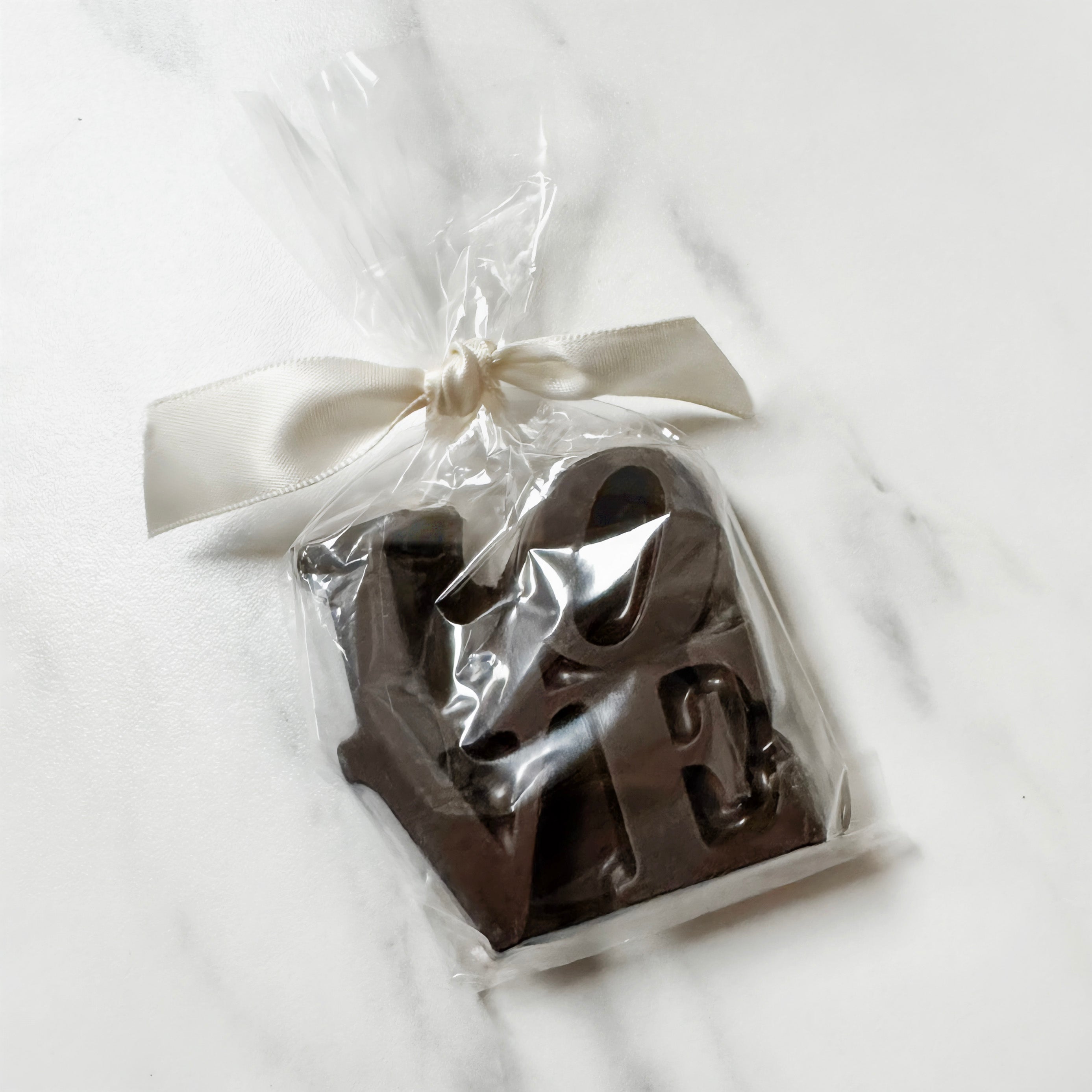 Chocolate letters Philly 'LOVE' in a clear cellophane bag with a ivory white ribbon on a light background