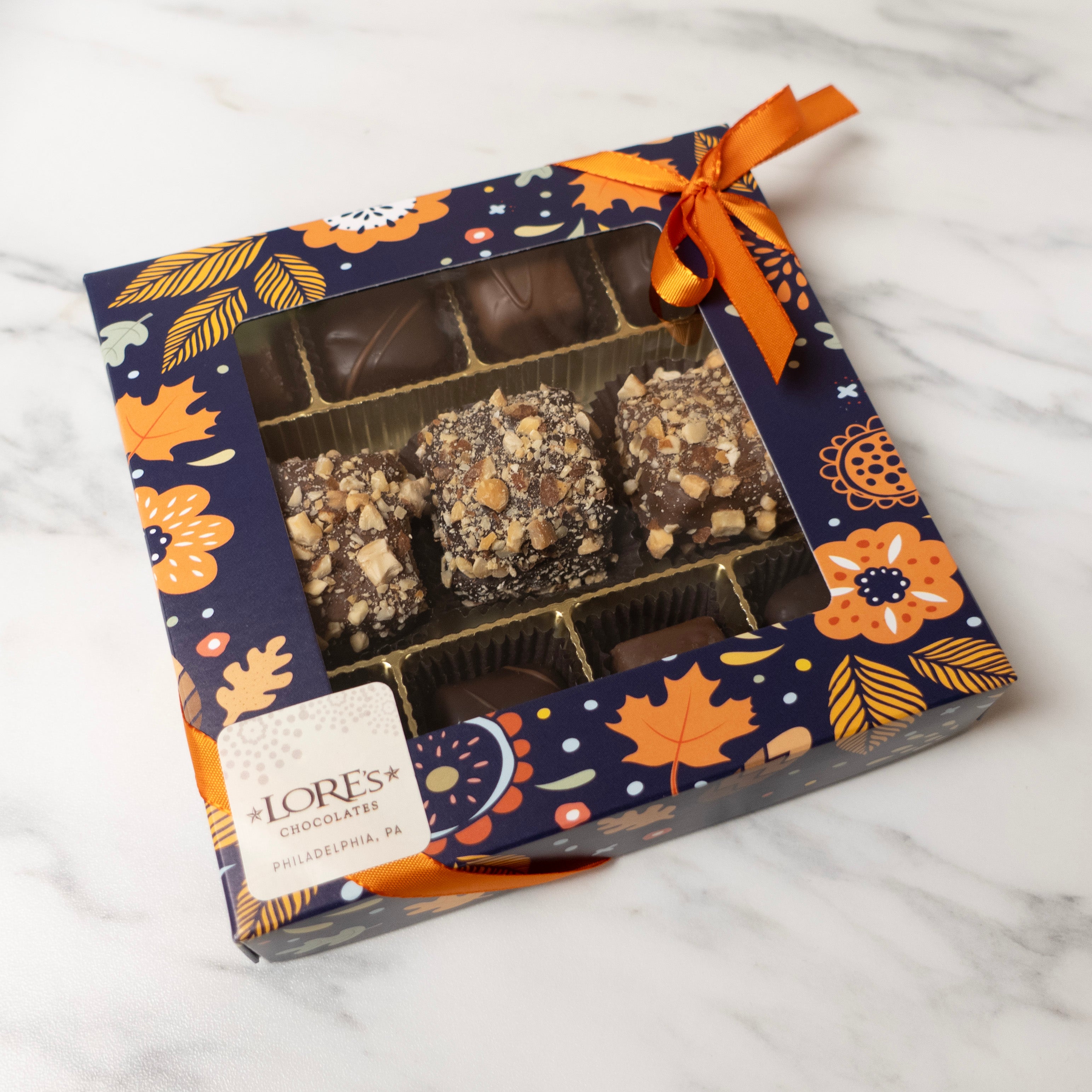 Box of chocolates with a decorative floral and autumn leaf pattern on a white background