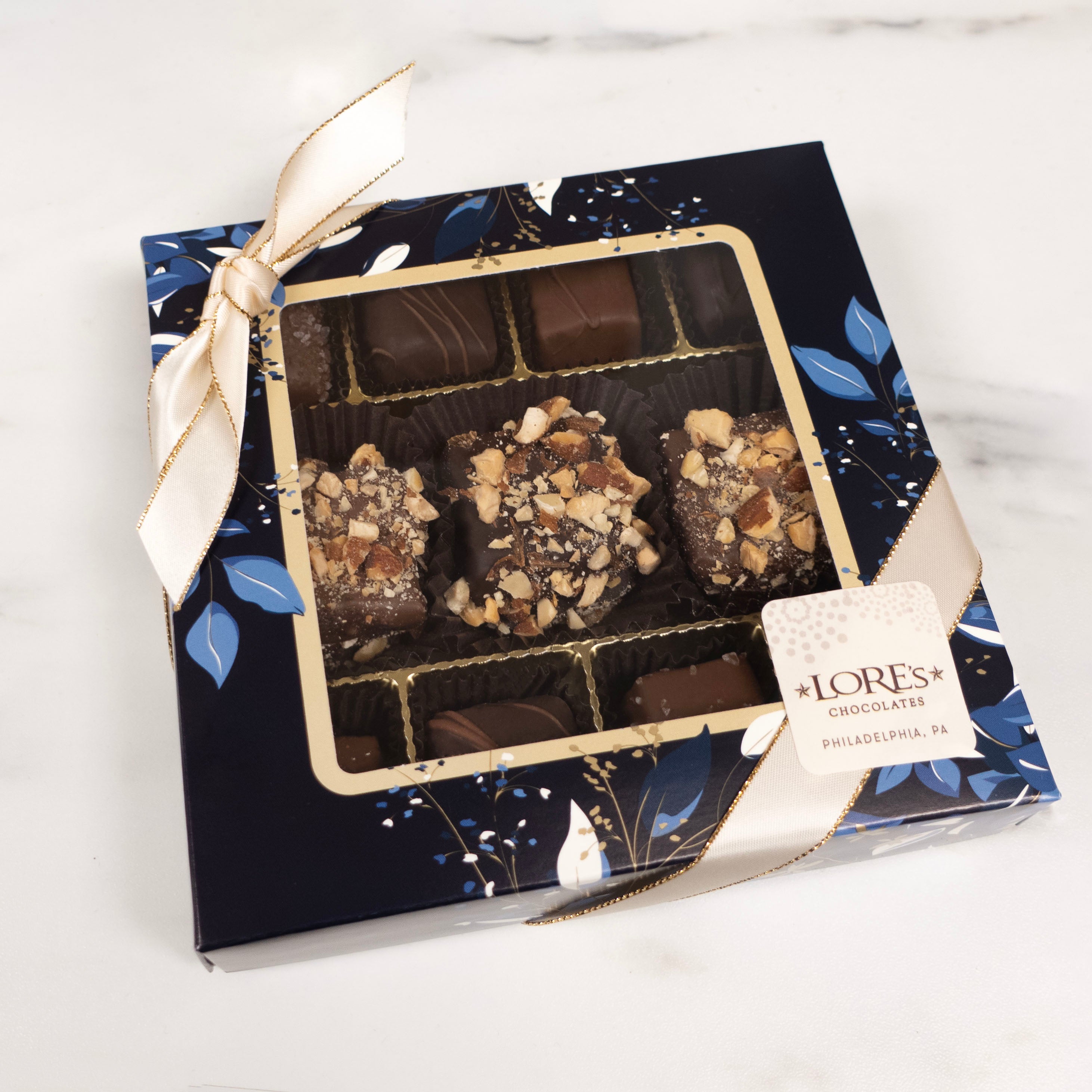 Box of assorted chocolates with a visible "Lore's Chocolates" sticker on a white background