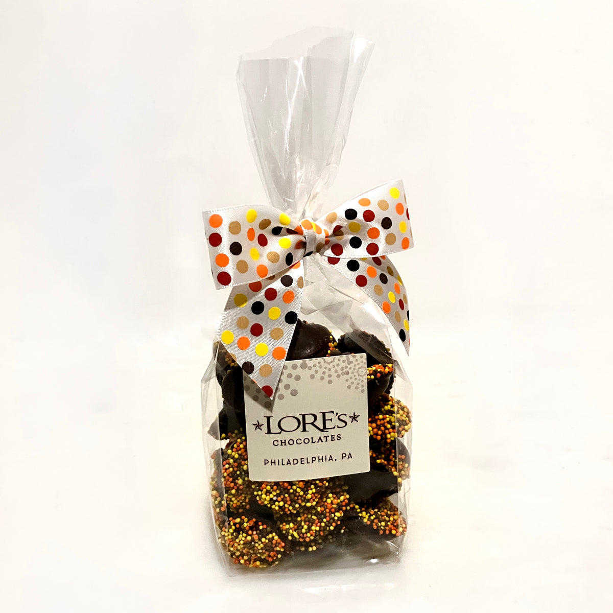 Bag of chocolate nonpareils with a polka dot bow and LORES Chocolates label on a white background