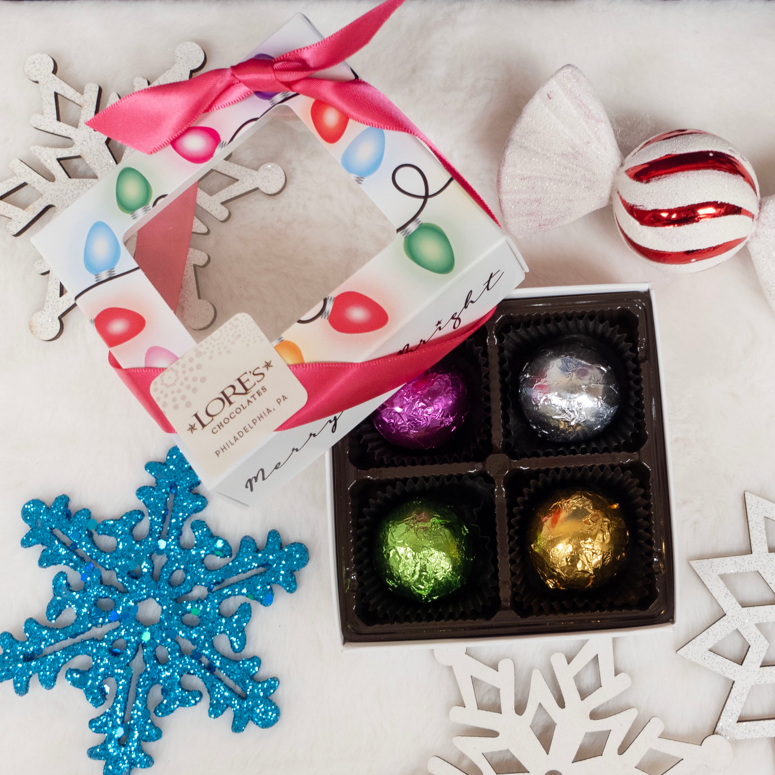 Box of chocolate truffles with festive packaging and Christmas decorations on a white surface