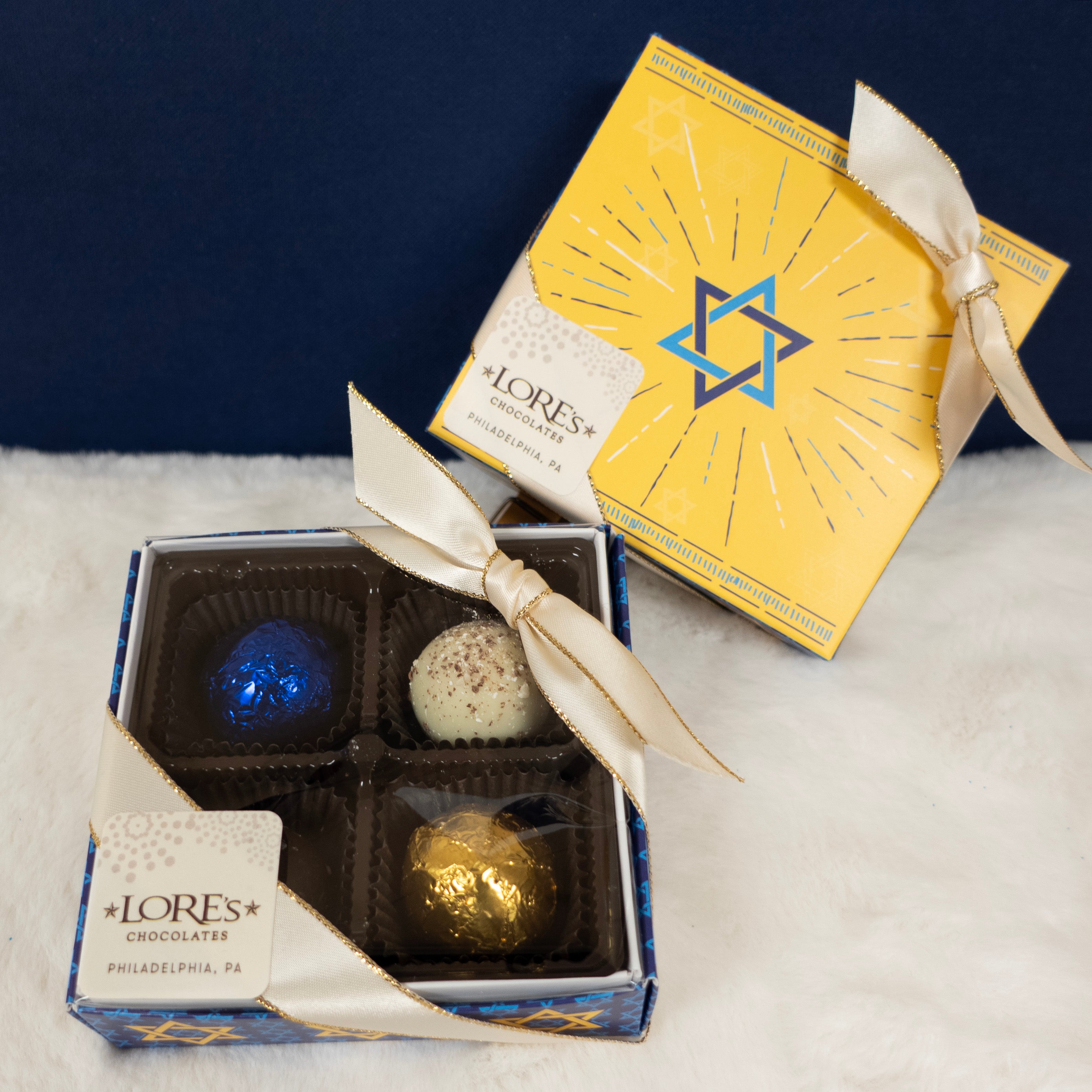 Box of chocolates with a yellow box featuring a star of david design on a textured surface.
