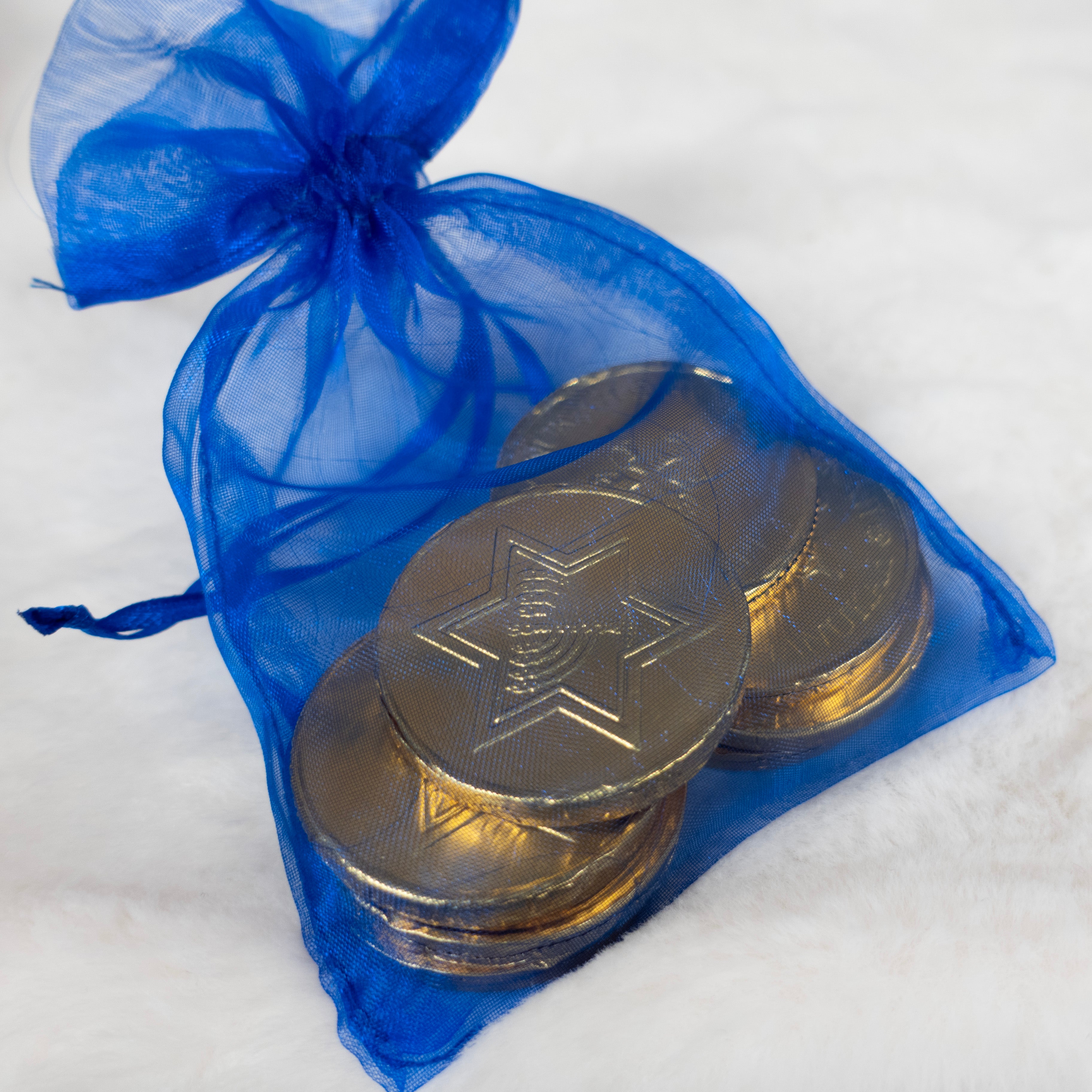 Gold coins with a star of david design in a blue drawstring bag on a white background