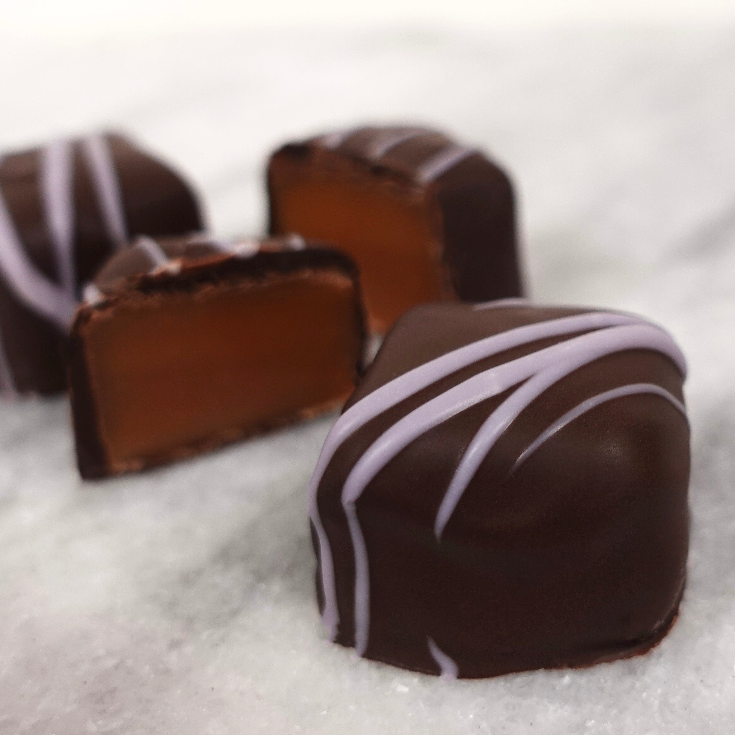 Chocolate candies with light purple drizzle on a white background