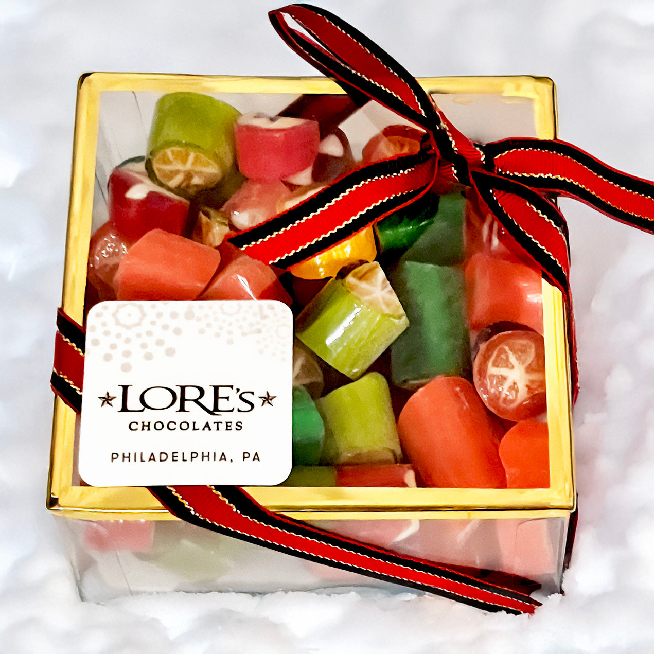 Box of colorful hard candies with a red and black ribbon and a Lore's Chocolates label.