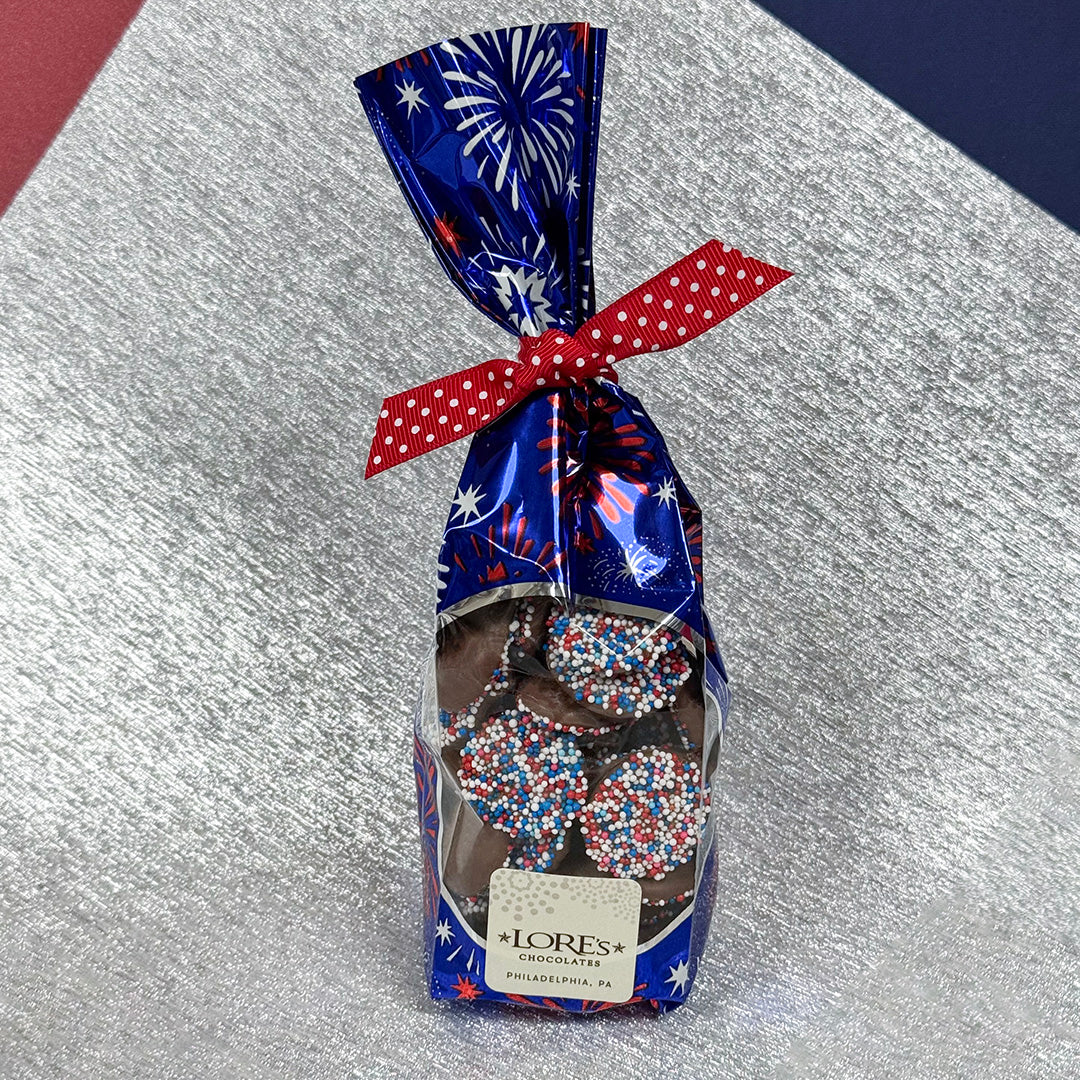 Packaged chocolate nonpareils with a festive design on a textured surface - Lore's Chocolates in Philadelphia