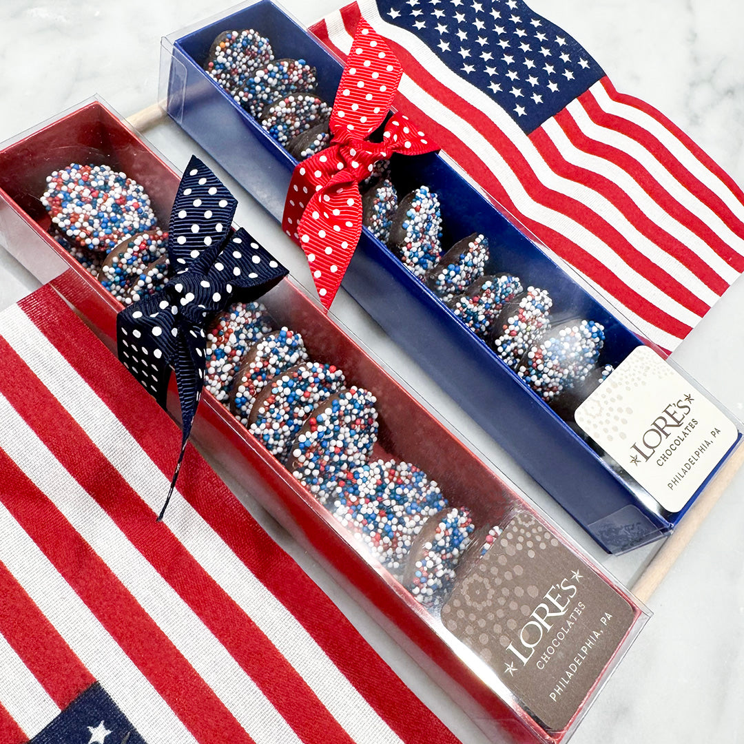 Chocolate nonpareils treats in a box with patriotic ribbons and an American flag on a white background - Lore's Chocolates in Philadelphia