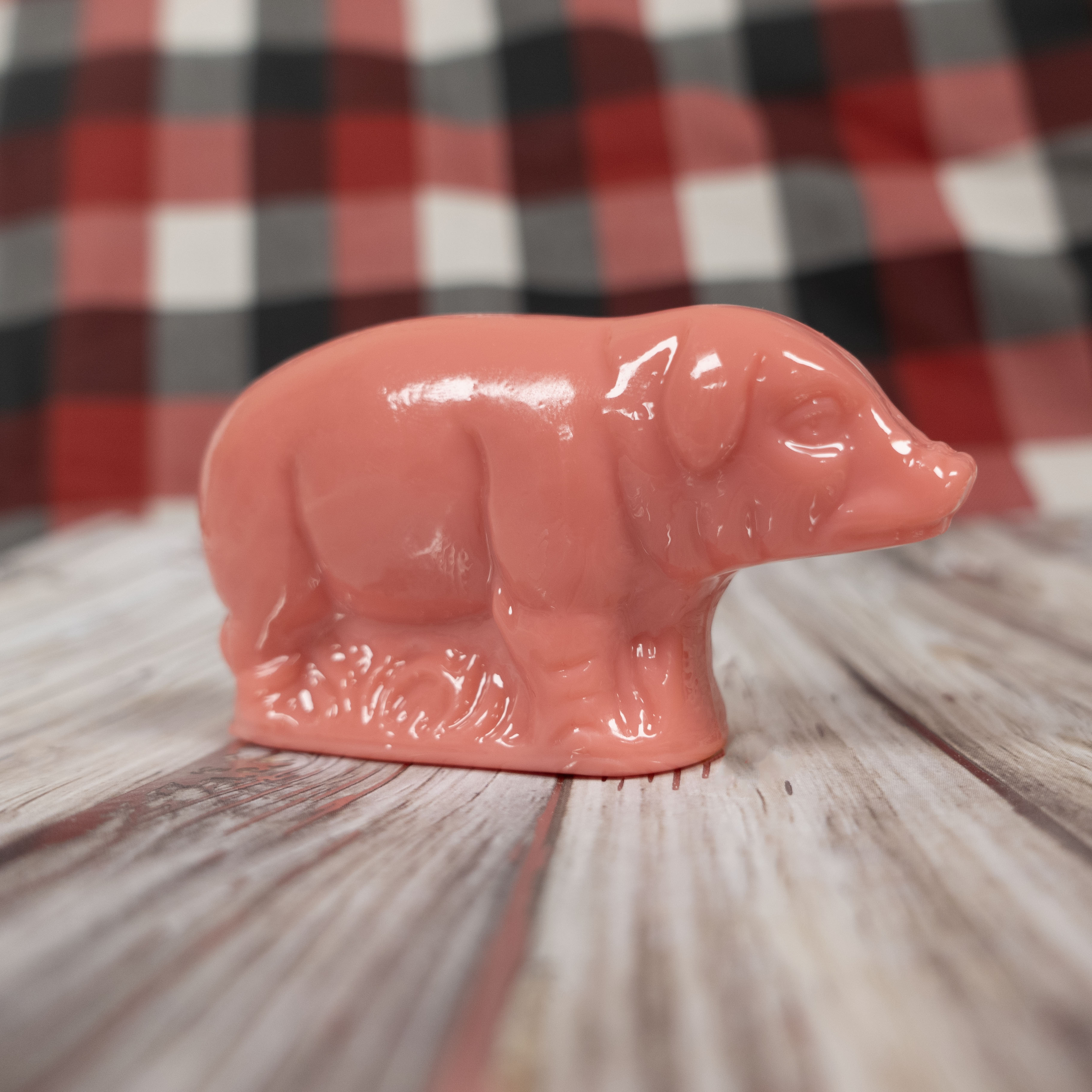 Pink pig candy figurine on a wooden surface with a plaid background