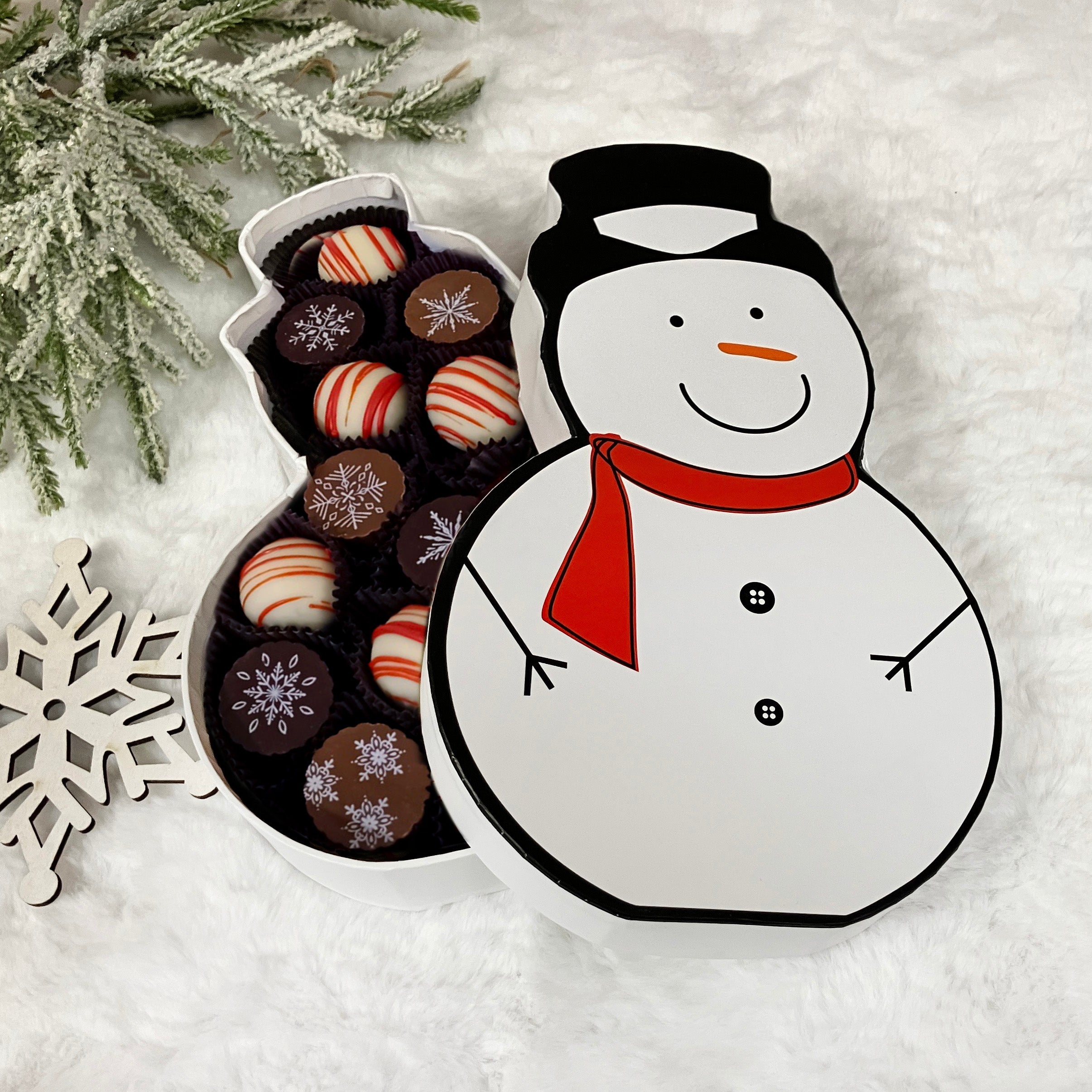 Snowman-shaped chocolate box with truffles on a snowy background