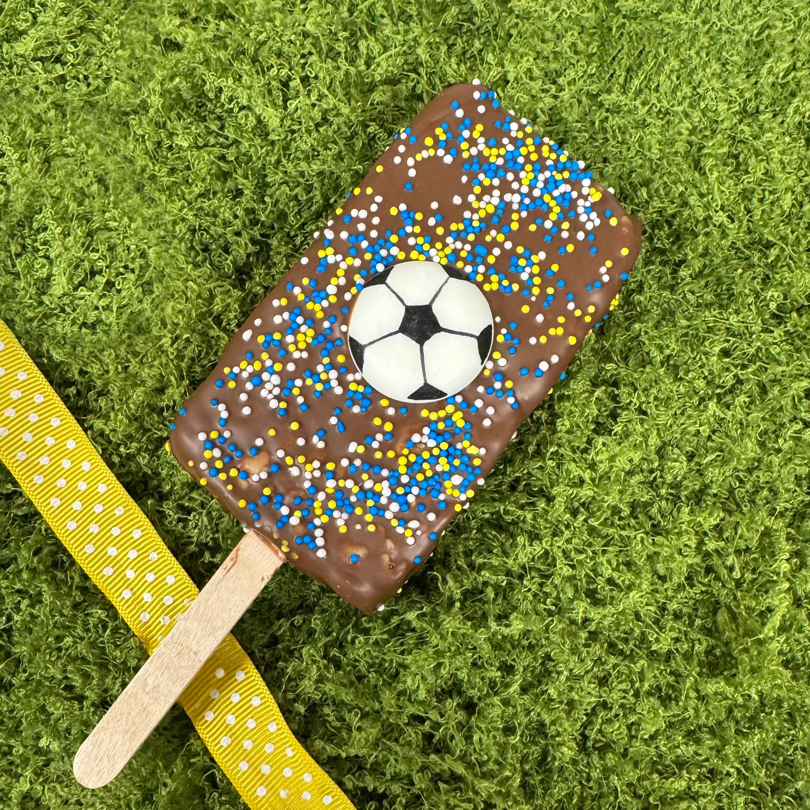 Chocolate-covered rice krispie bar with a soccer ball design on a green grass background - made by Lore's Chocolates in Philadelphia for FIFA 2026