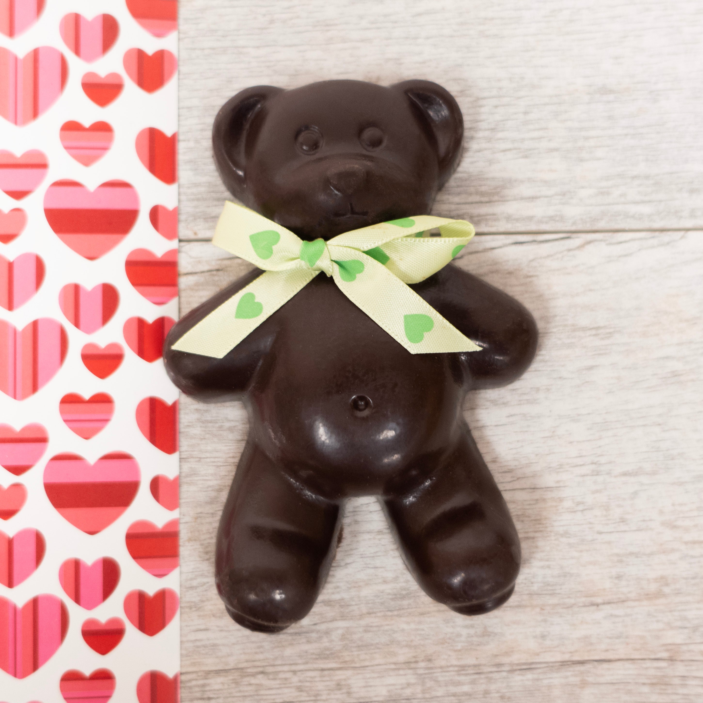 dark chocolate teddy bear with a green bow with hearts for valentine's day