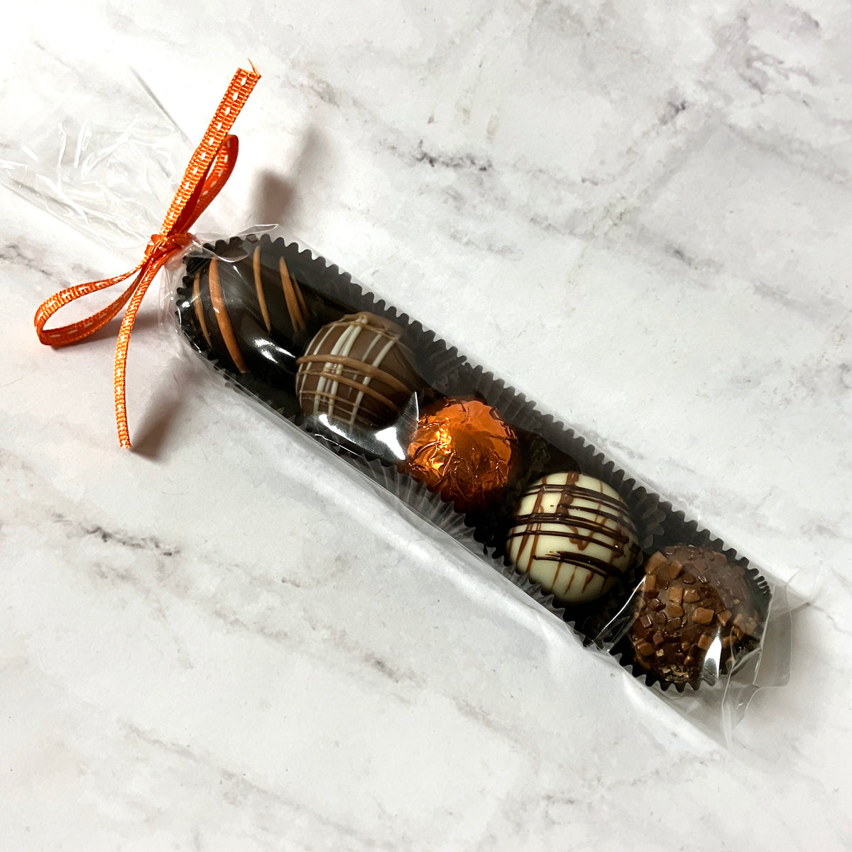 Packaged assortment of chocolate truffles on a marble surface