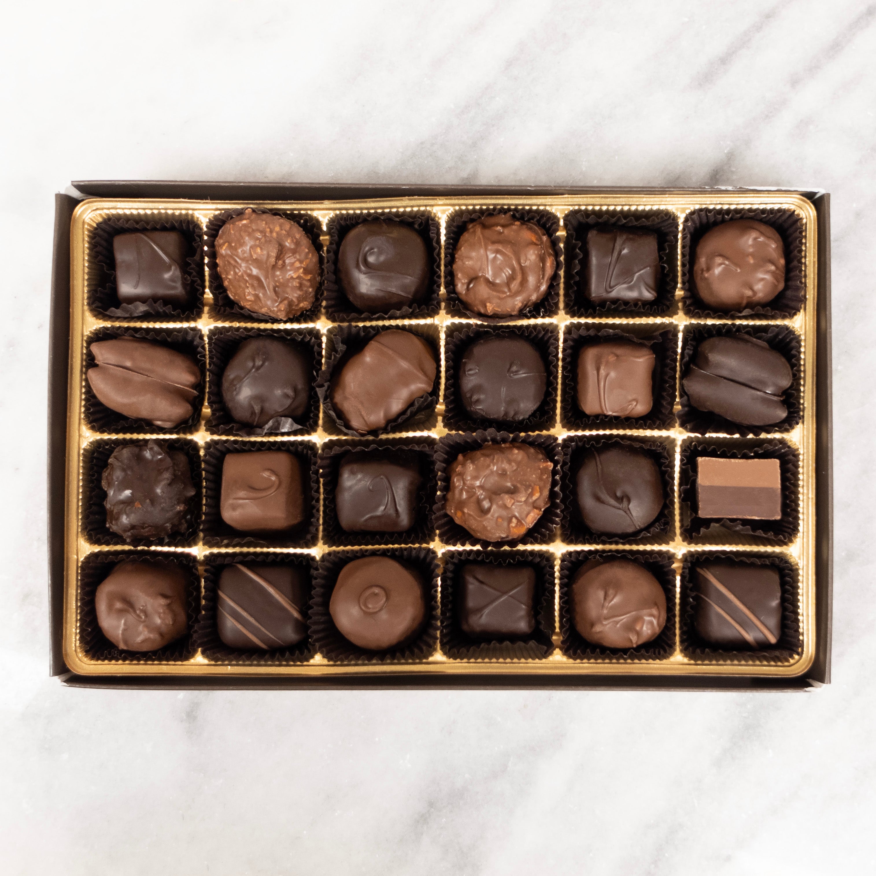 Box of assorted chocolates on a white marble surface