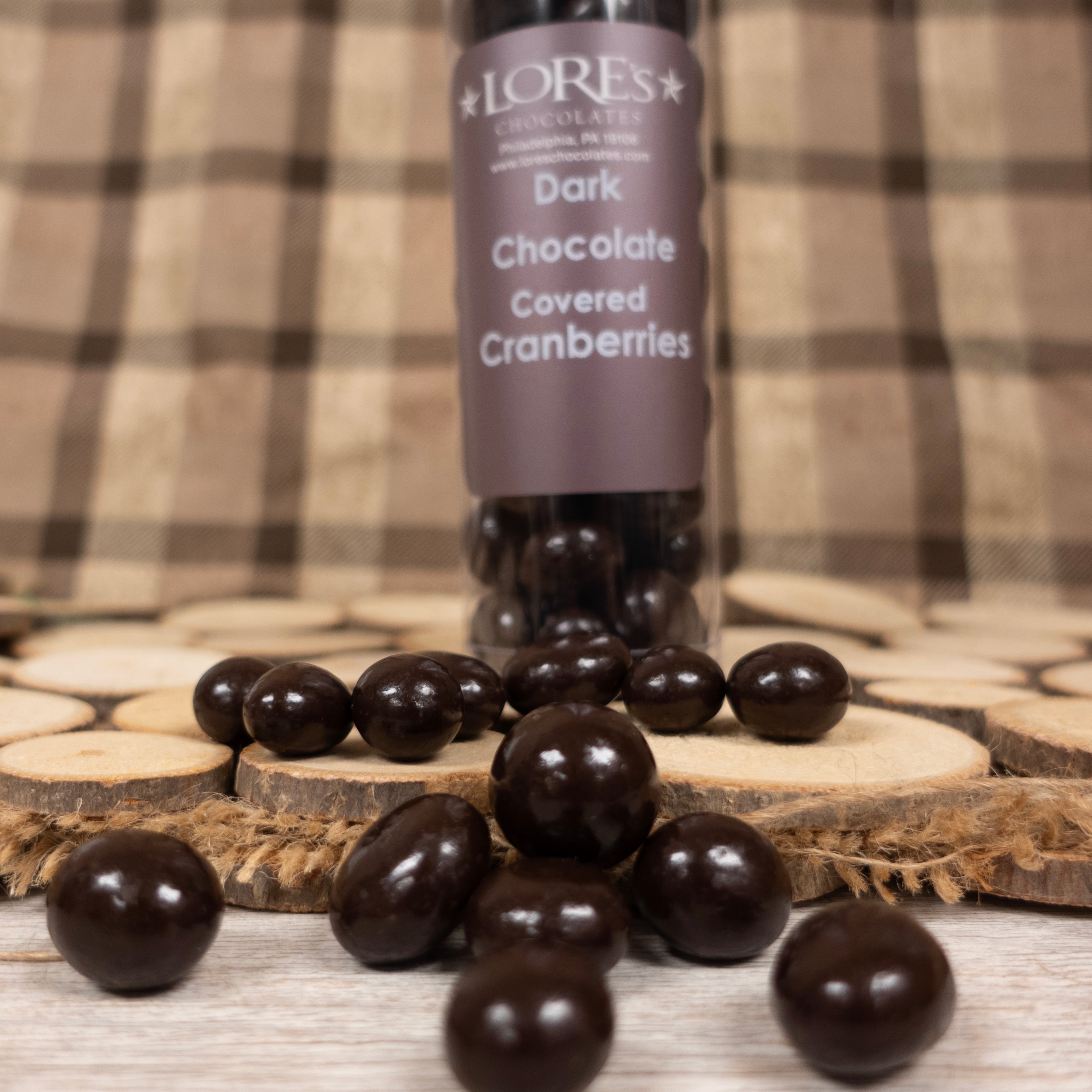 Dark chocolate covered cranberries with a container labeled with 'LORES' on a wooden surface.