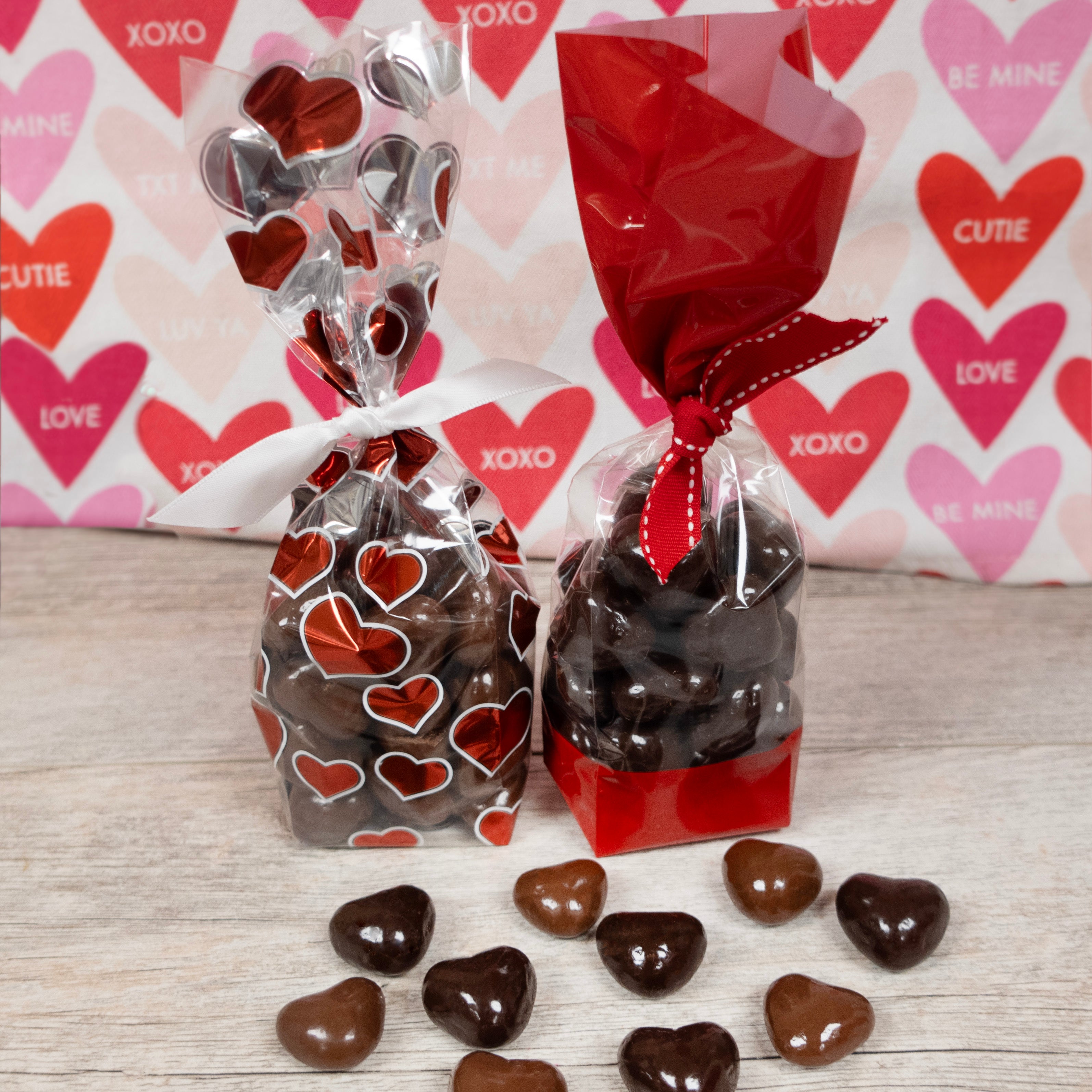 Heart-Shaped Milk and Dark chocolate caramels sold by Lore's Chocolates, packaged in a valentine's day cellophane bags, left is milk chocolate, right is dark chocolate caramel