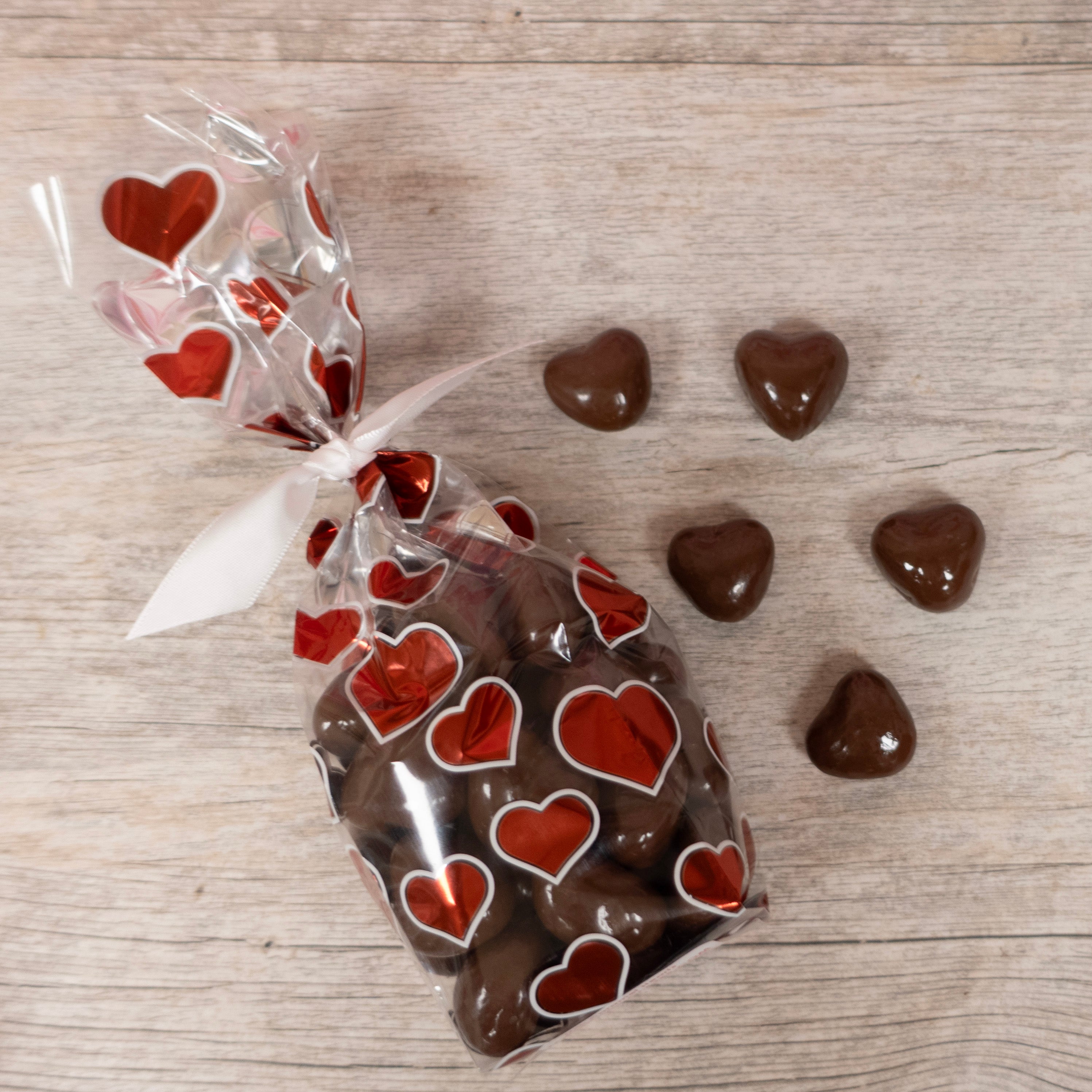 Heart-Shaped Milk chocolate caramels sold by Lore's Chocolates, packaged in a valentine's day cellophane bag with hearts 