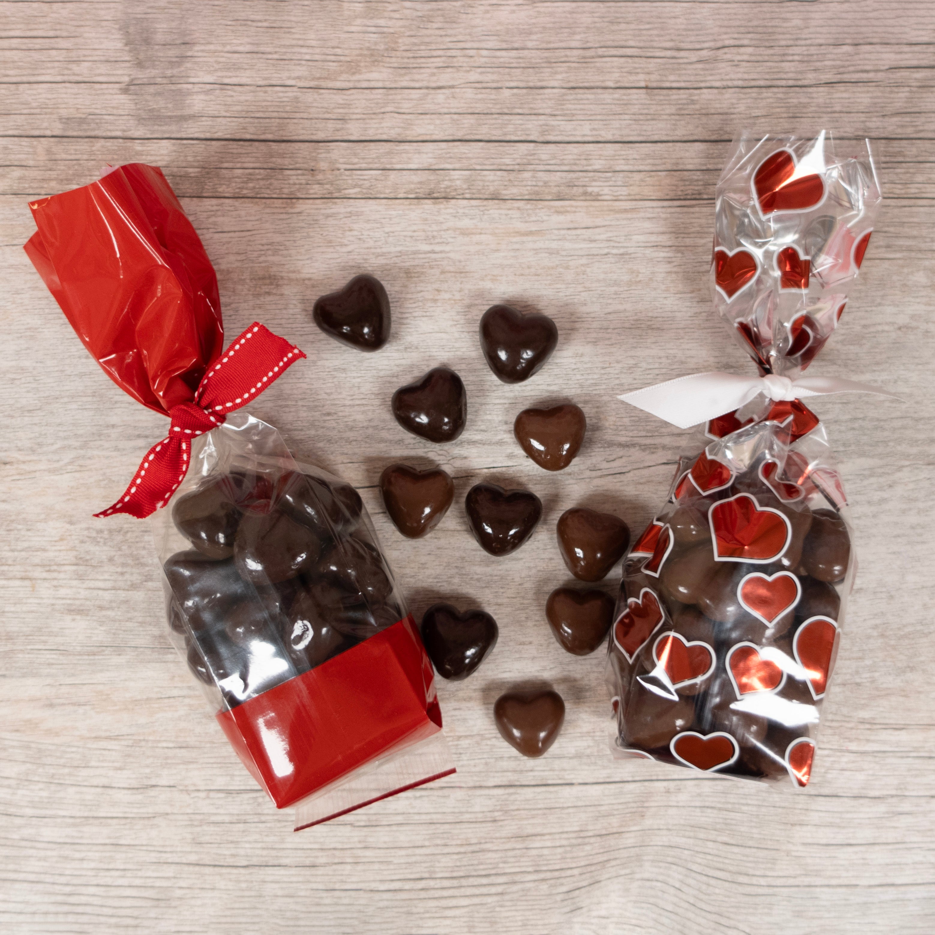 Valentine's Cellophane bags full of heart-shaped chocolate caramels - dark chocolate on left, milk chocolate on right, assorted loose chocolate caramels in the center