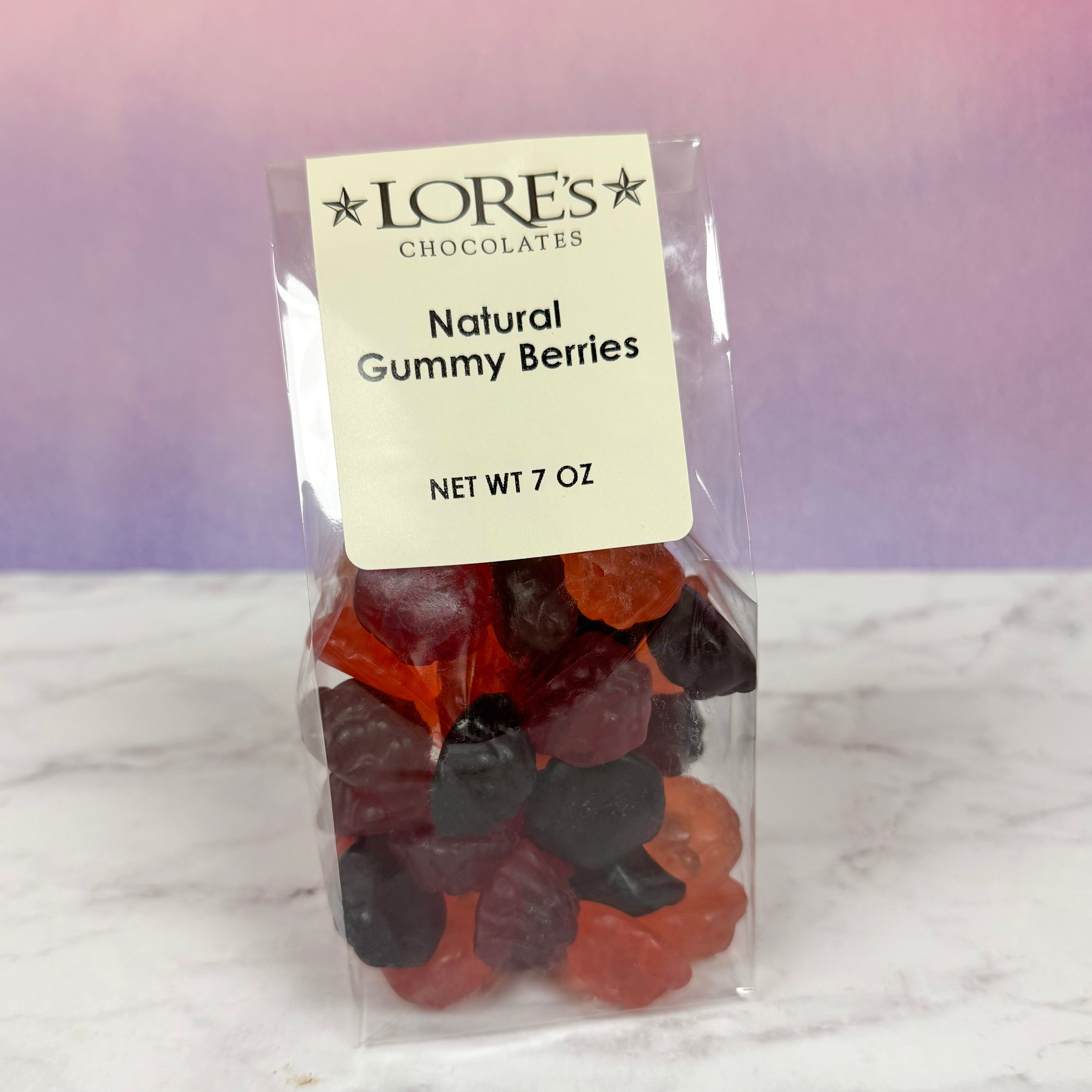 Packaged natural gummy berries with a Lore's Chocolates label on a marble surface.