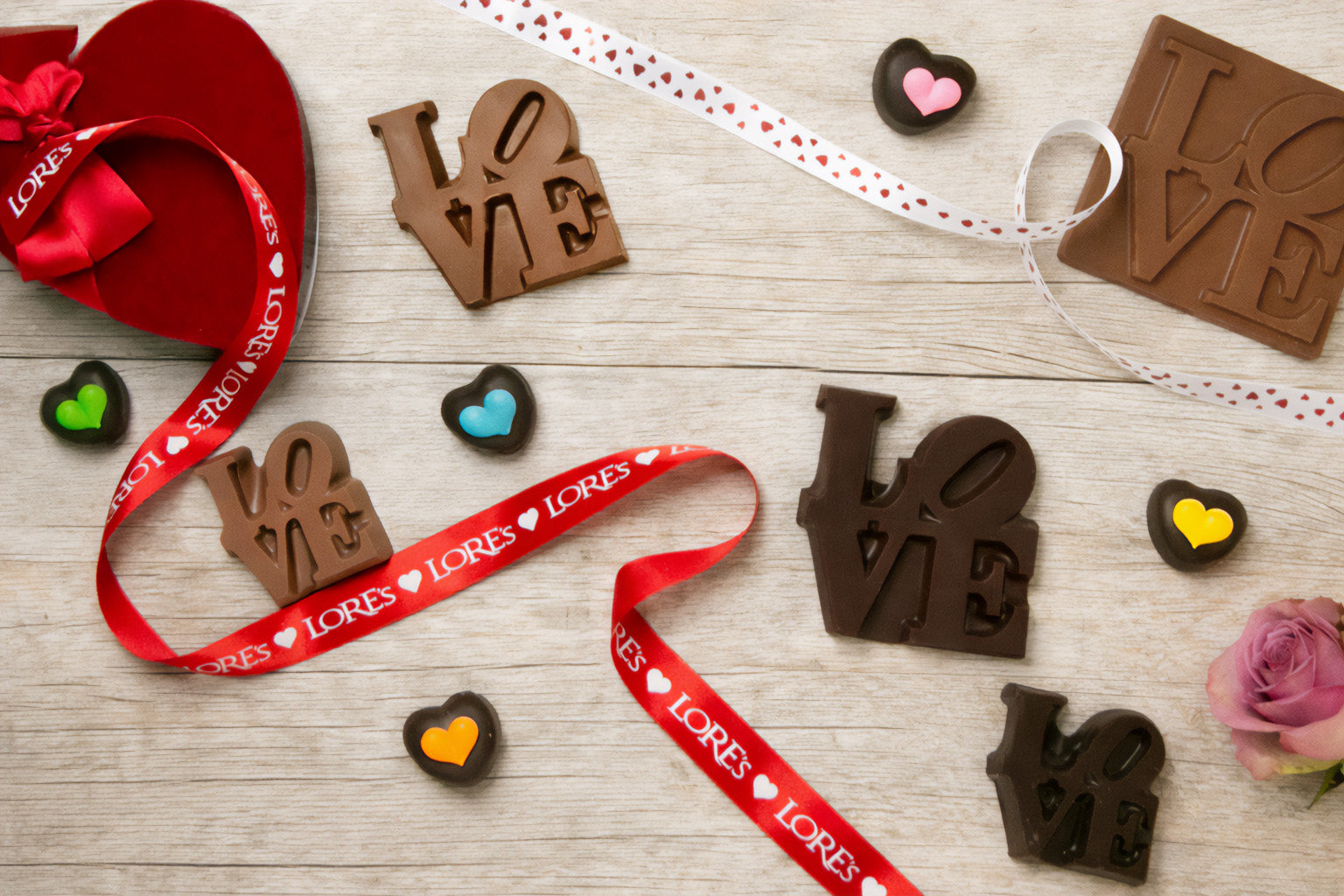 Chocolate 'LOVE' shaped candies from Lore's Chocolates in philadelphia with ribbons on a wooden surface