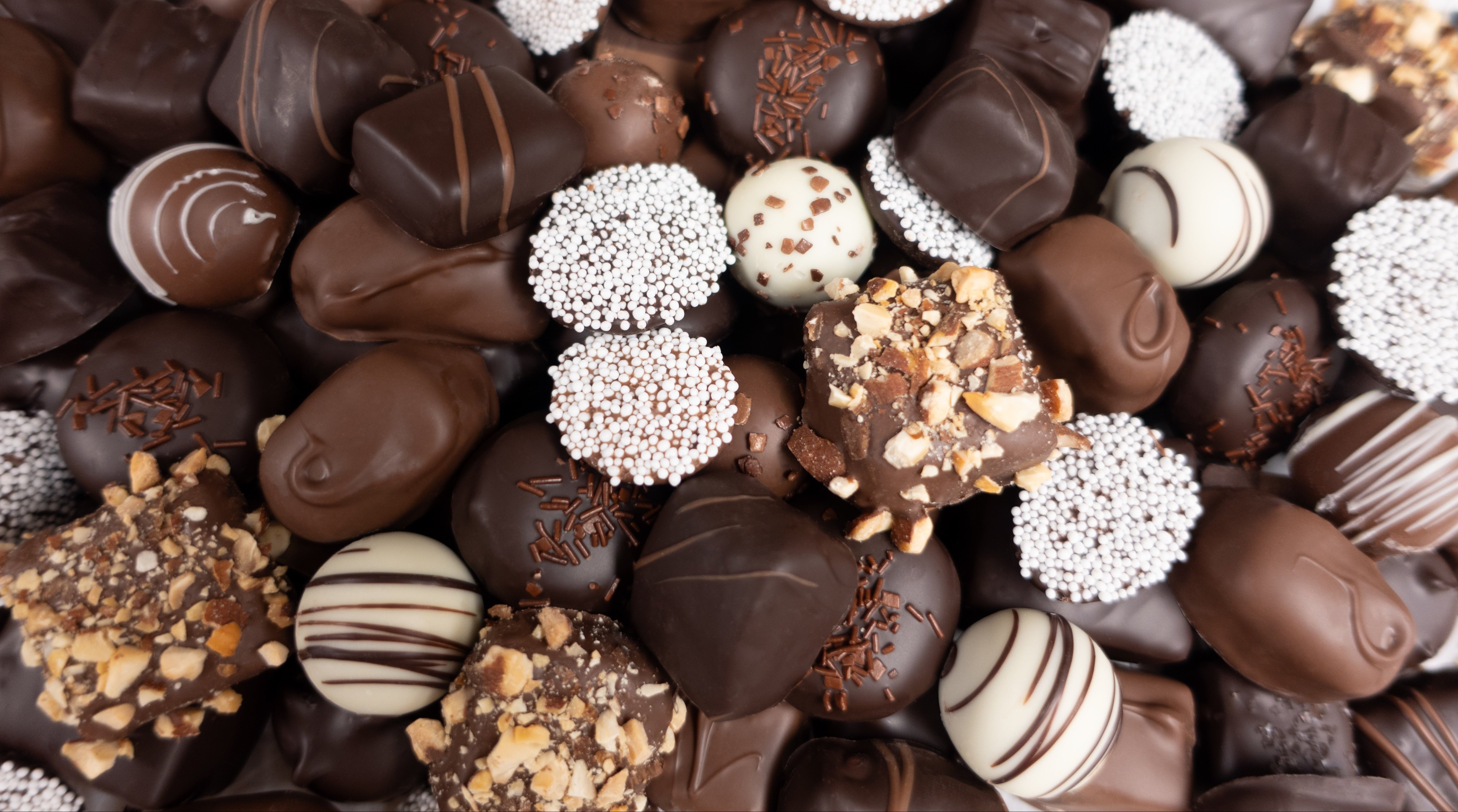Assorted chocolates &  truffles with various toppings on a white background