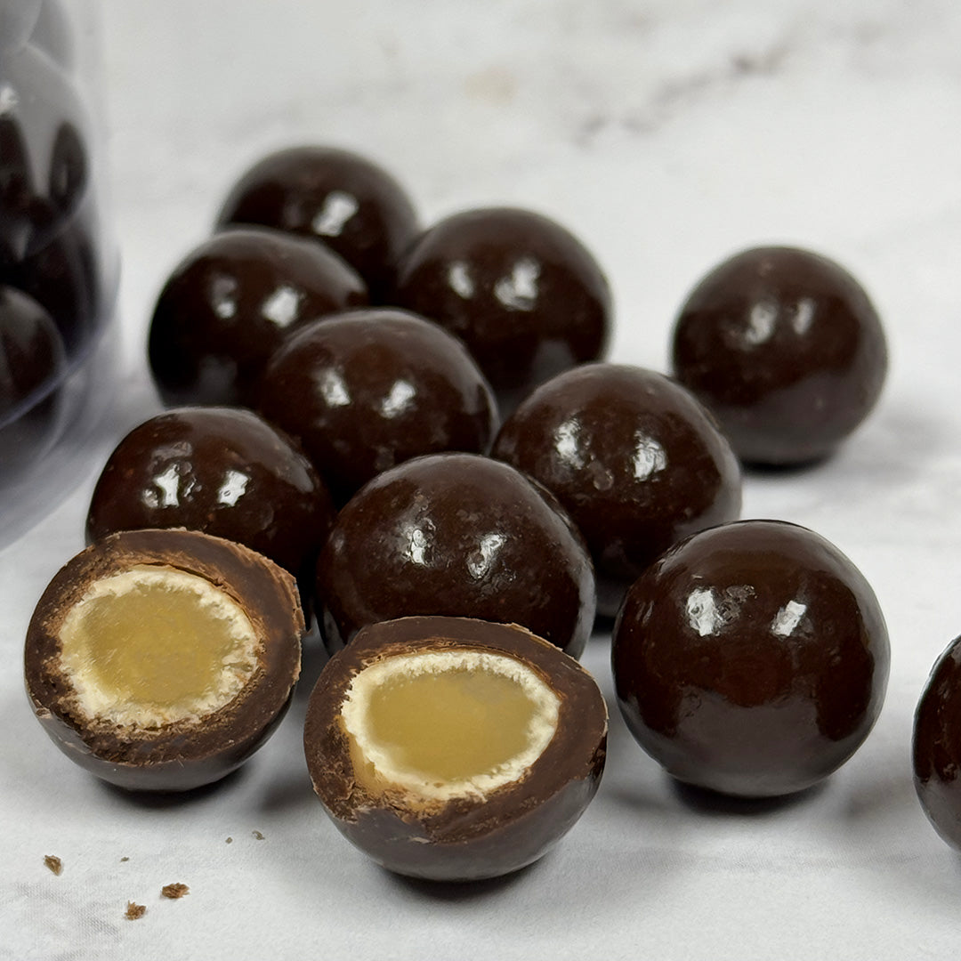 Chocolate-covered cabernet caramels with a visible filling on a marble surface
