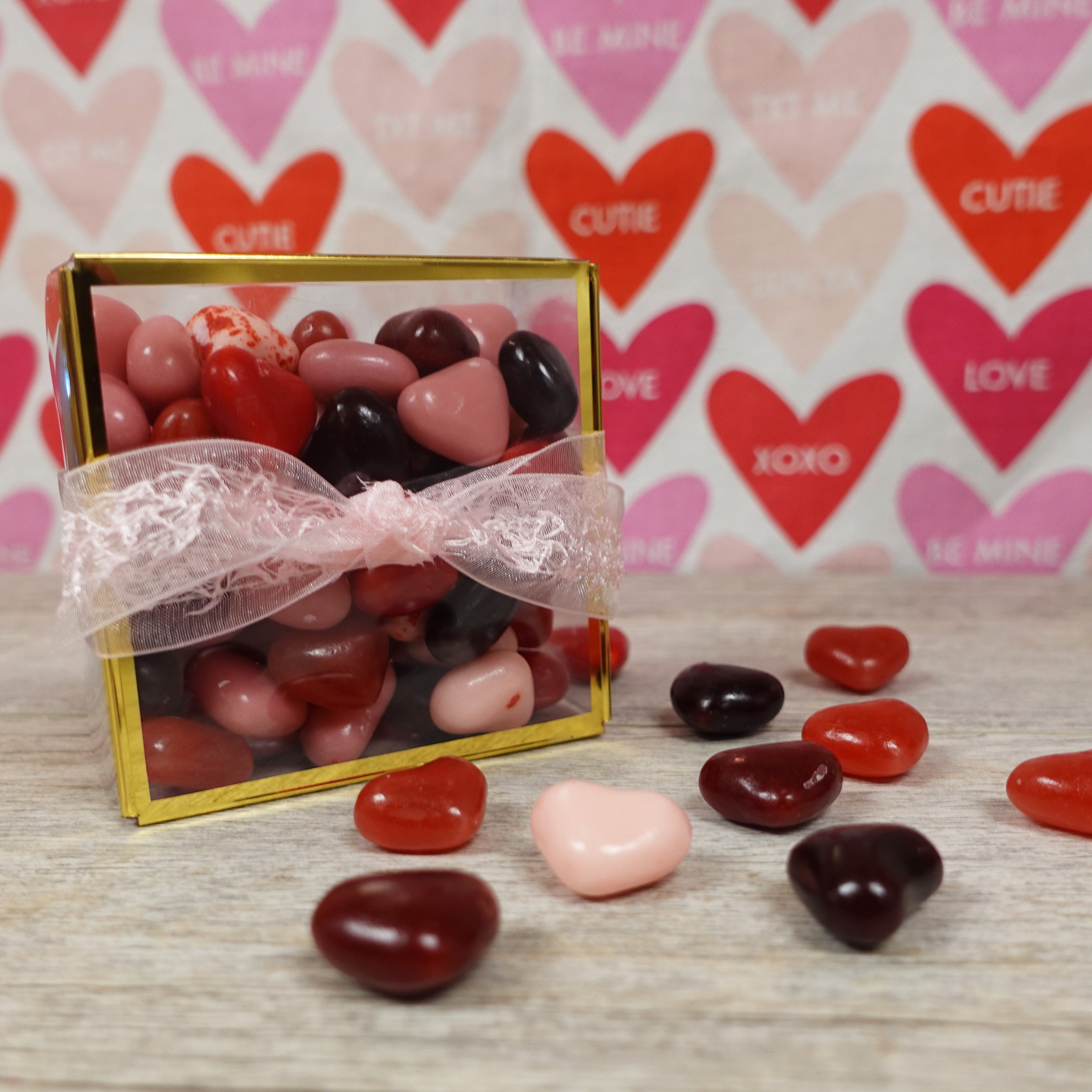 heart shaped jelly beans in various cherry flavors and different pink and red colors for valentine's day. packaged in a clear box with gold accent and lacey pink ribbon - sold at lore's chocolates in philadelphia