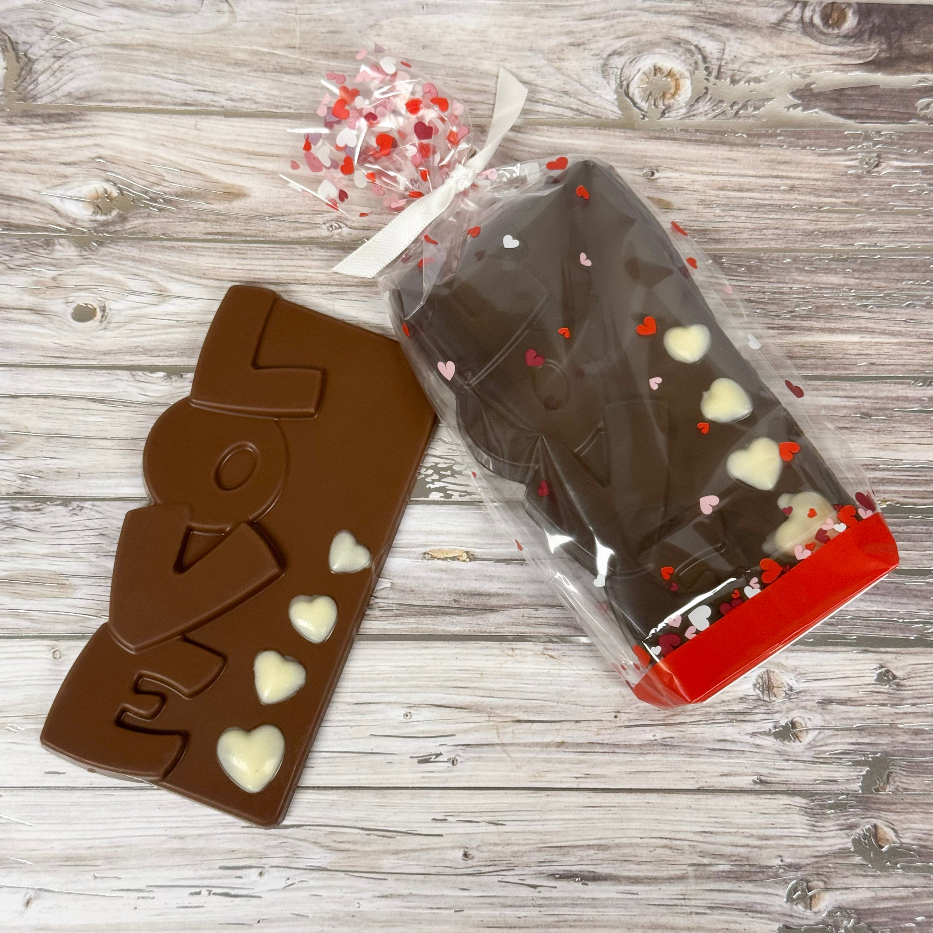 Chocolate bar with 'LOVE' and heart designs on a wooden surface