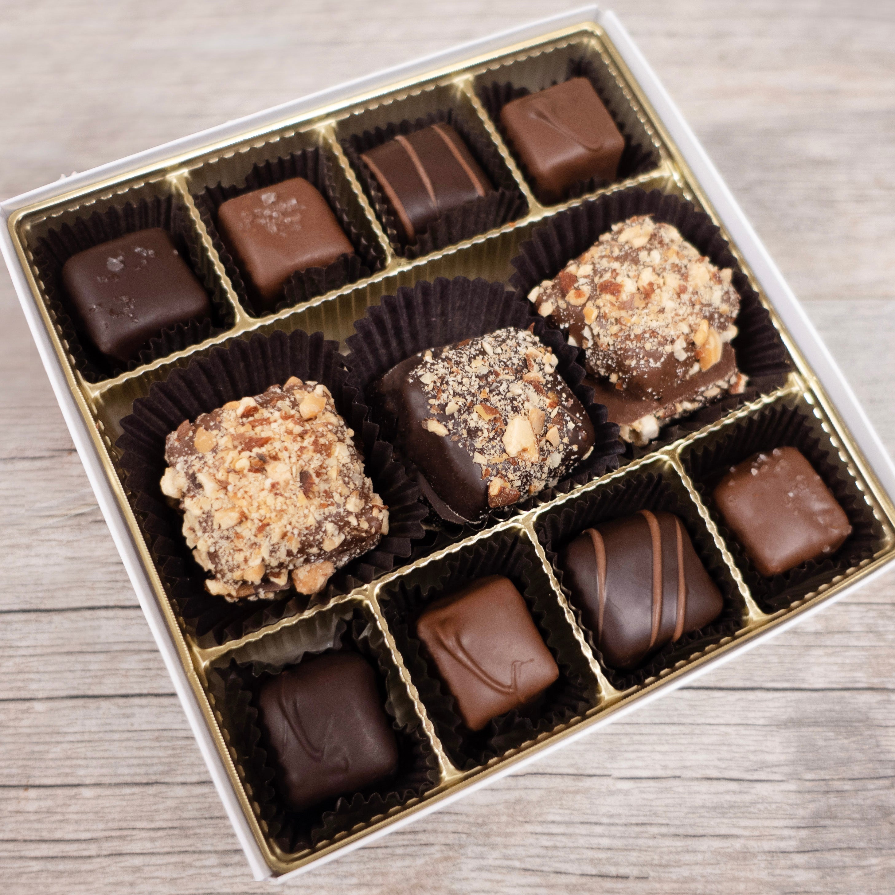 Assorted chocolate candies in a box on a wooden surface