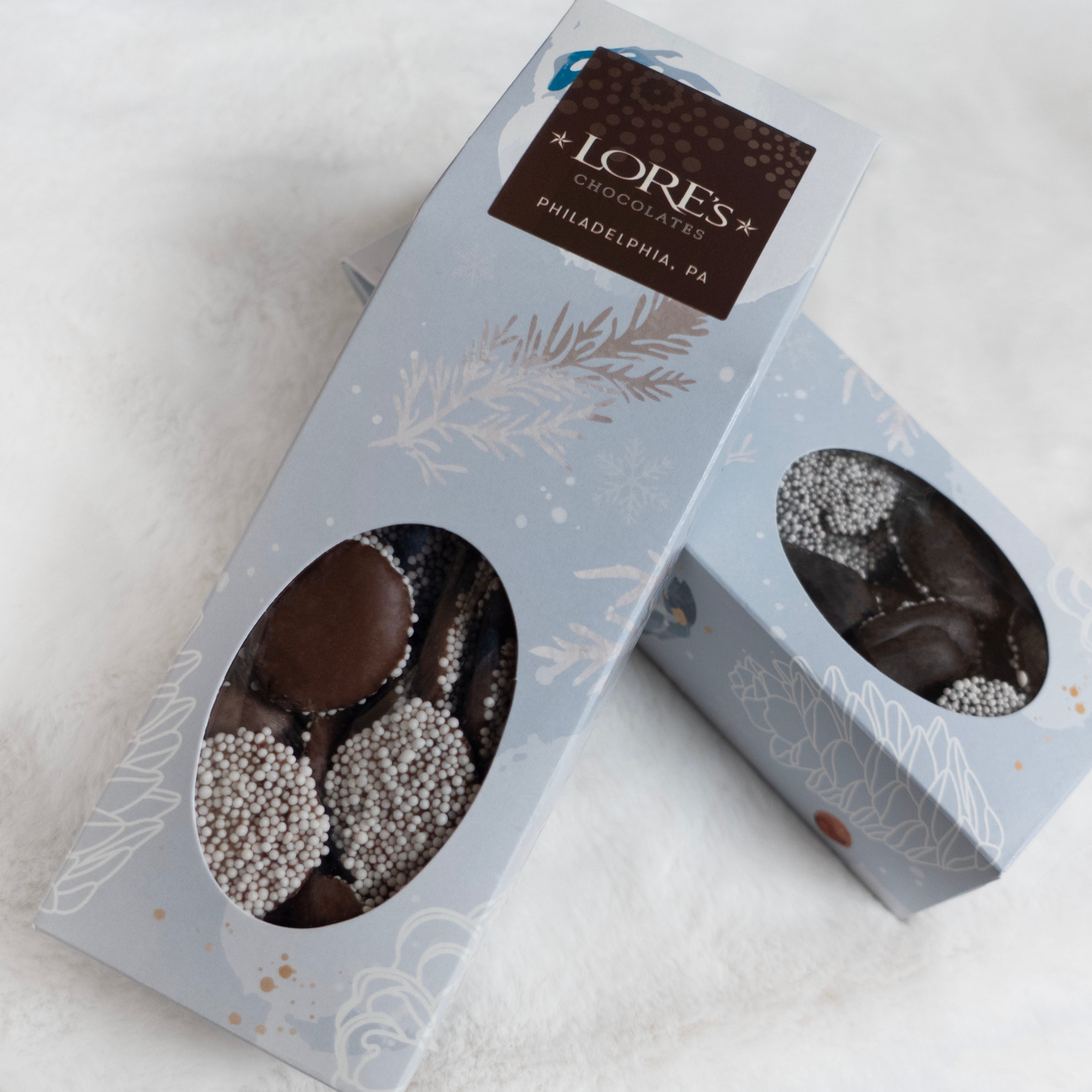 Two boxes of Lore's Chocolates nonpareils on a white surface