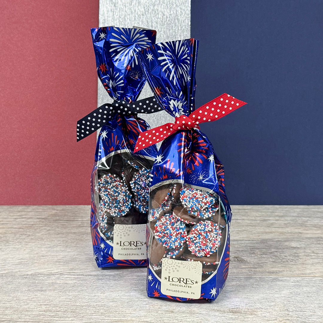 Chocolate nonpareils in decorative patriotic packaging for America 250 with festive designs on a wooden surface.  Lore's Chocolates in Philadelphia