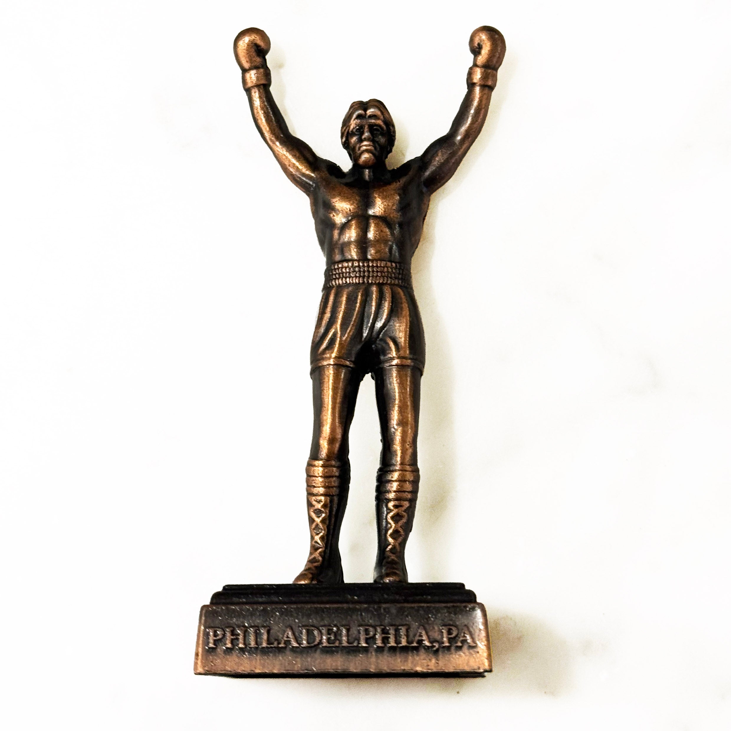 Bronze statue of Rocky from Philadelphia with raised fists on a white background