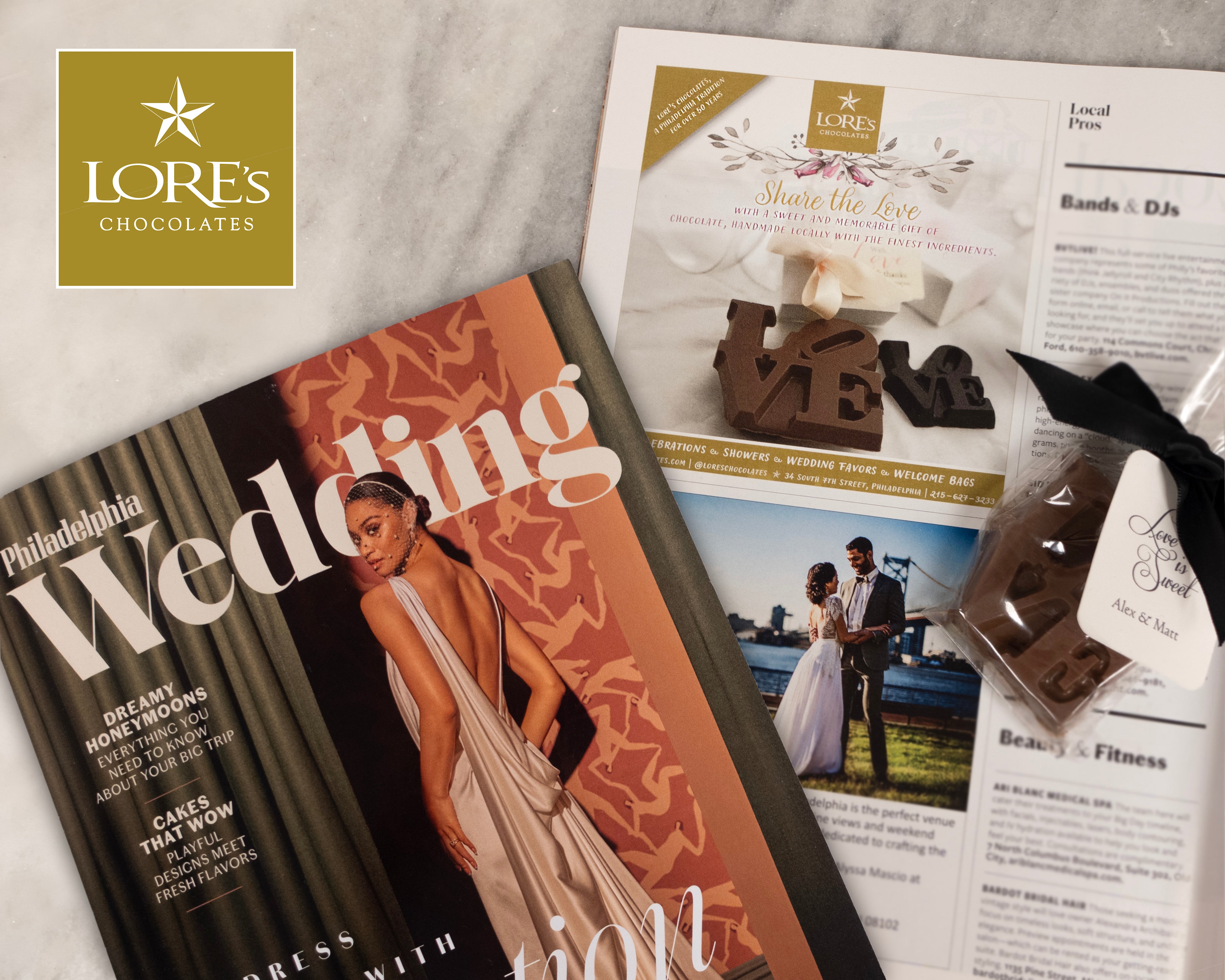 Philadelphia Wedding Magazine and LORE'S Chocolates branding on a marble surface.