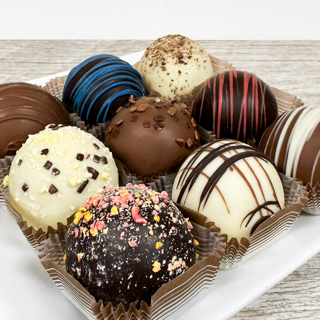 Assorted queen-sized, large dessert chocolate truffles on a wooden surface, sold at Lore's Chocolates in Philadelphia