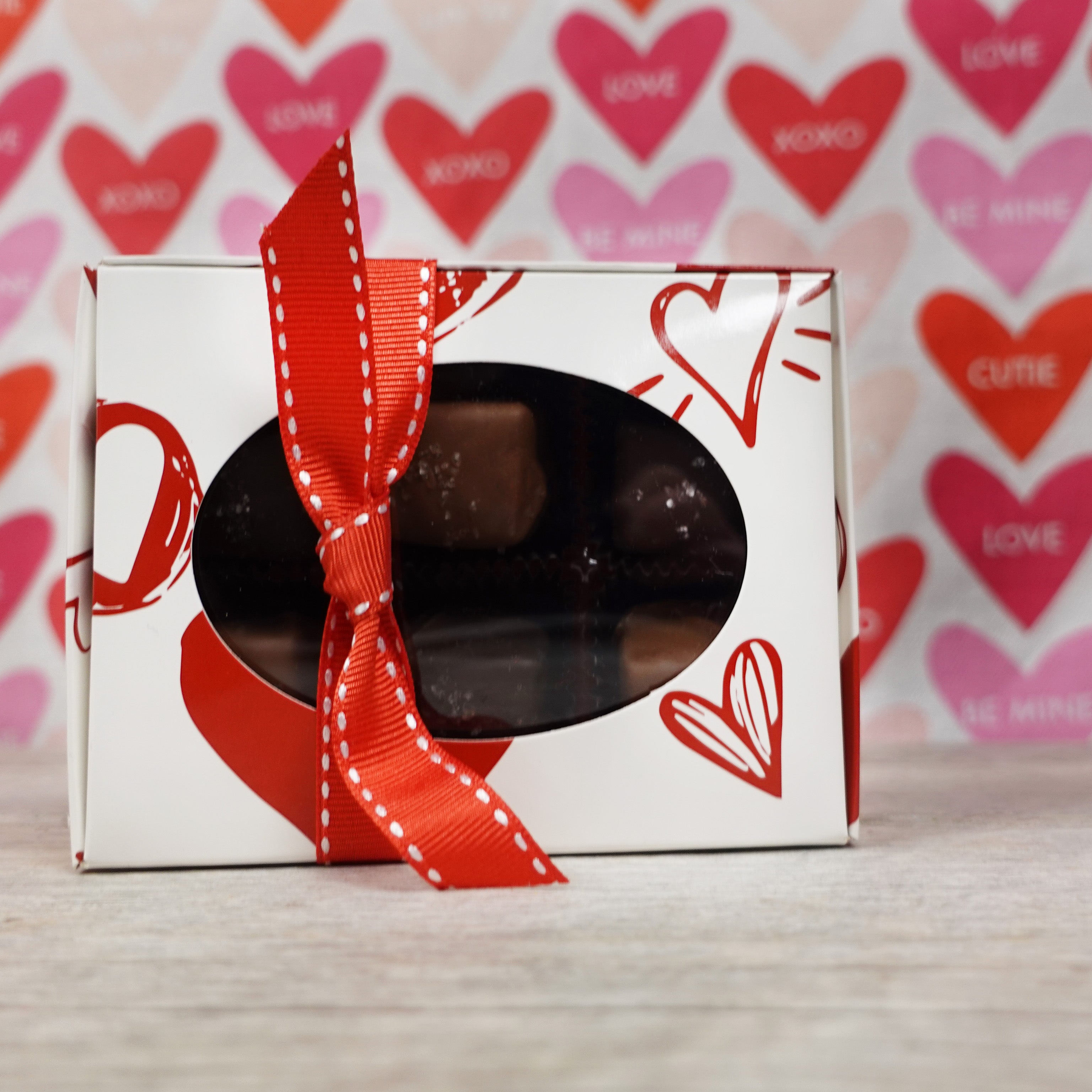 Lore's Chocolates Milk and Dark SEa SAlt Caramels in  6 pack white box with red doodle hearts and a red ribbon