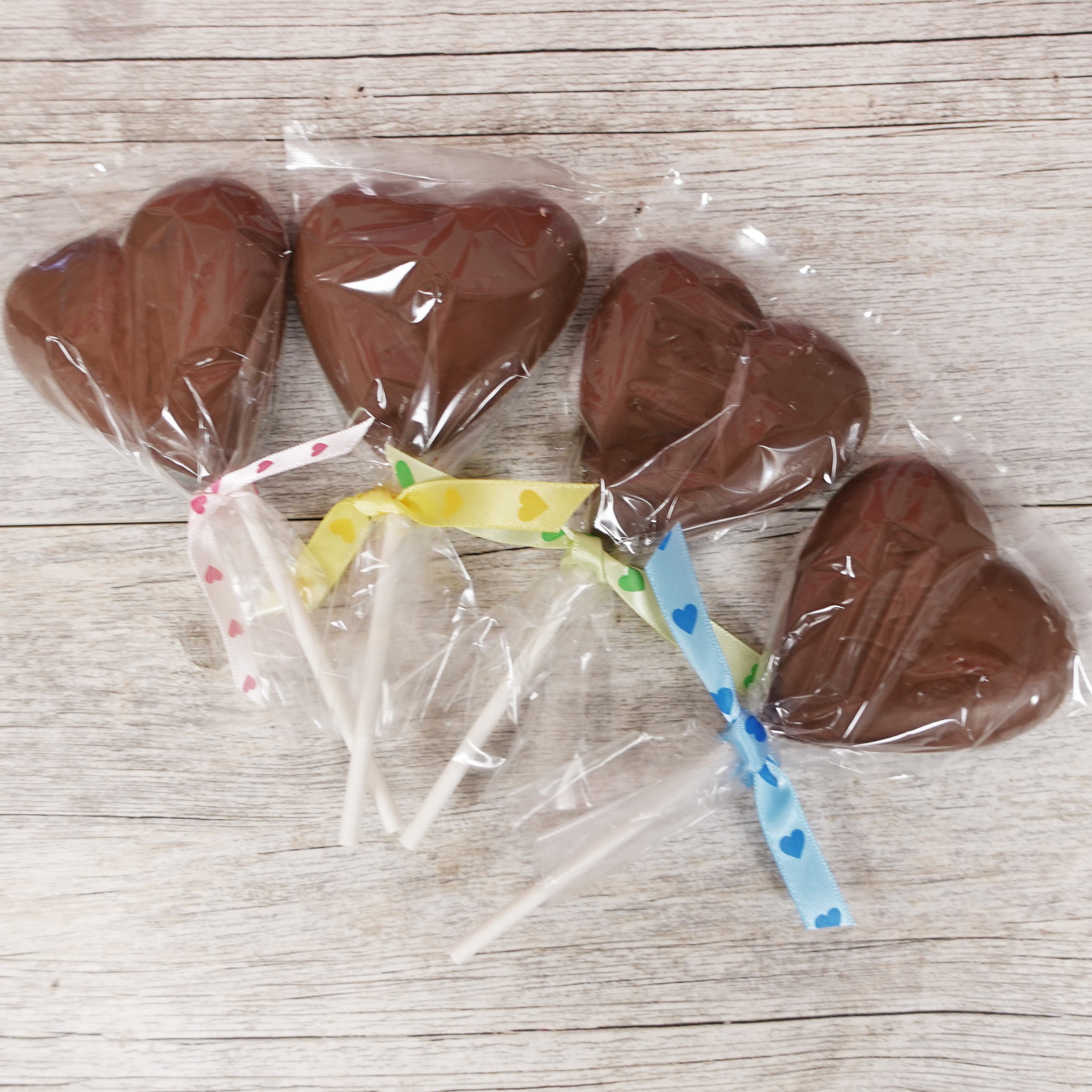 four chocolate lollipops made from Lore's Milk Chocolate with the inscription "To My Valentine" wrapped in cellophane and ribboned with different colored heart ribbons