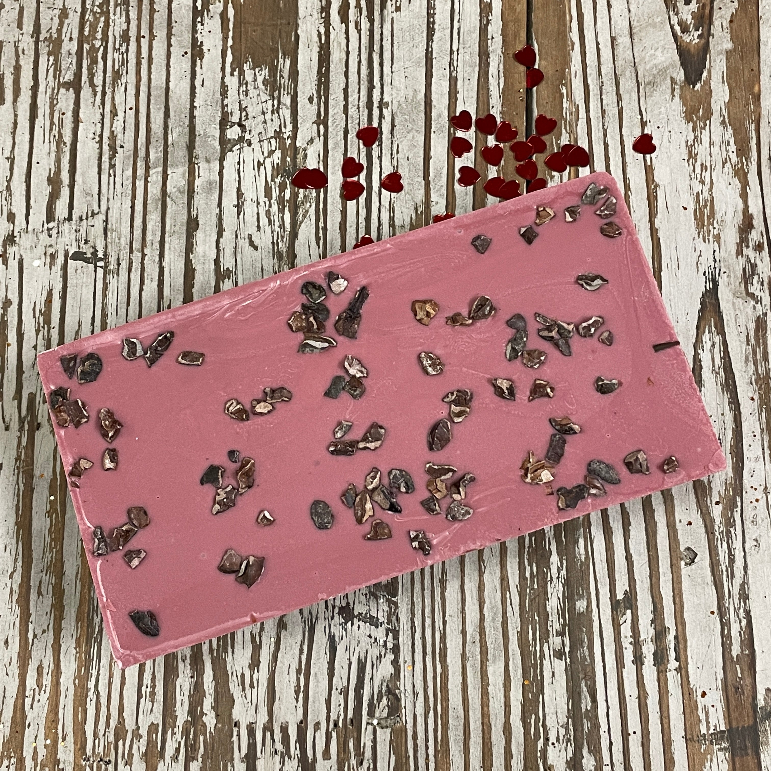 unwrapped bar of ruby chocolate with a bright pinkish ruby color, with cocoa nibs on top