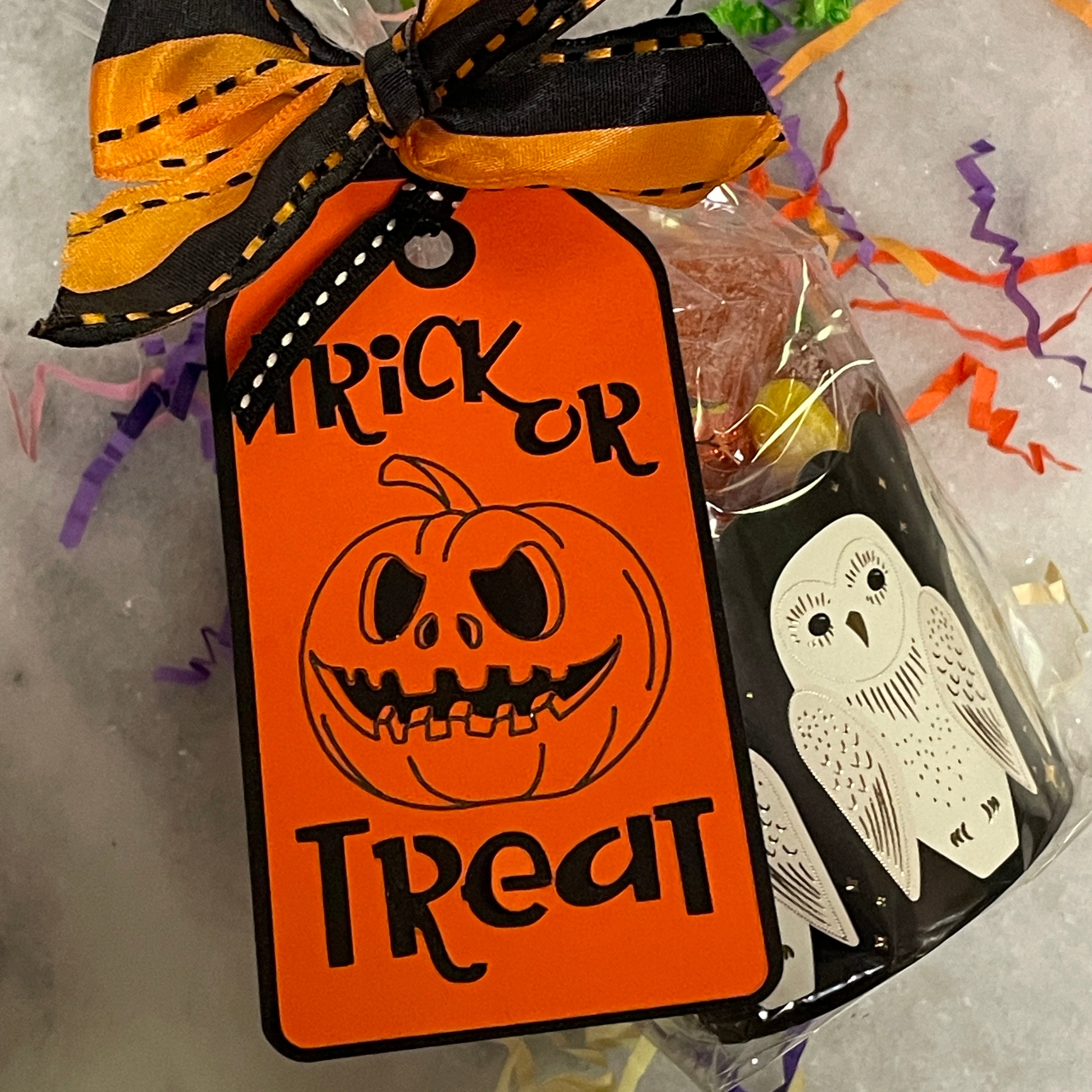 Orange and black Trick or Treat tag ribboned on a black favor cup with white owls